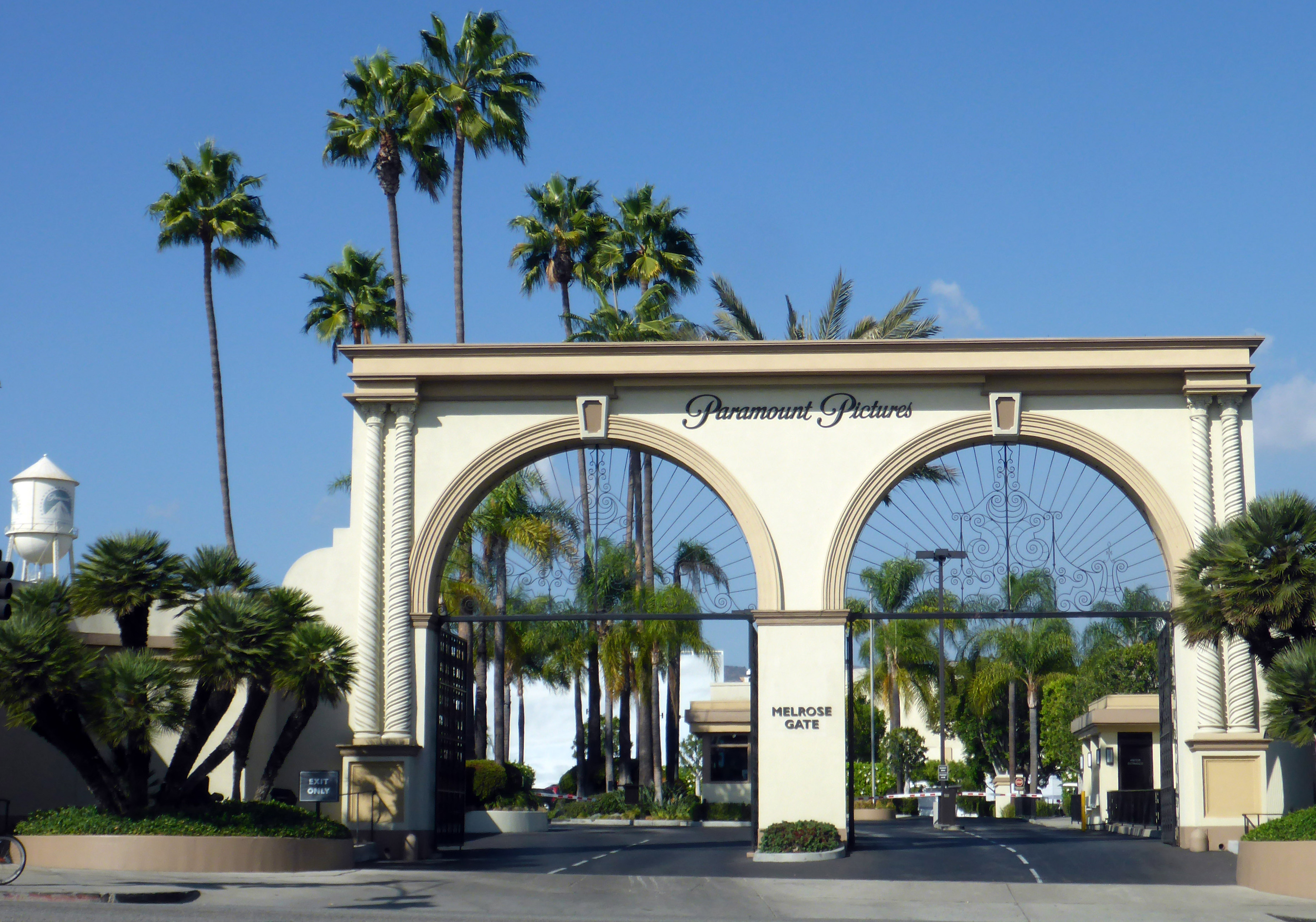 Ornate arched entrance gate of Paramount Pictures studio lot with palm trees.