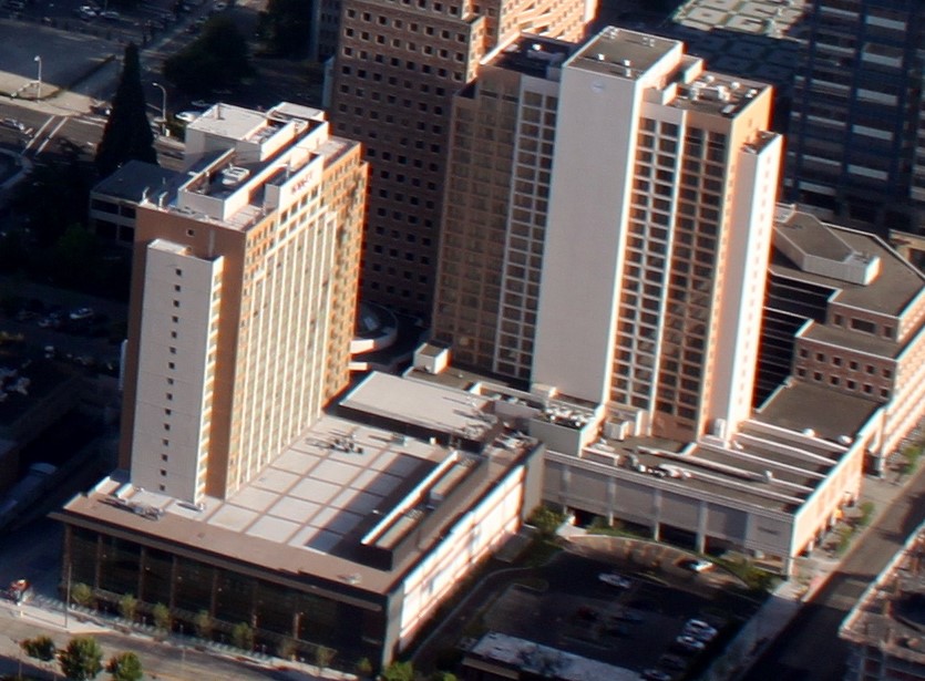 Aerial view of a hotel tower and surrounding high-rise buildings in a downtown urban core.