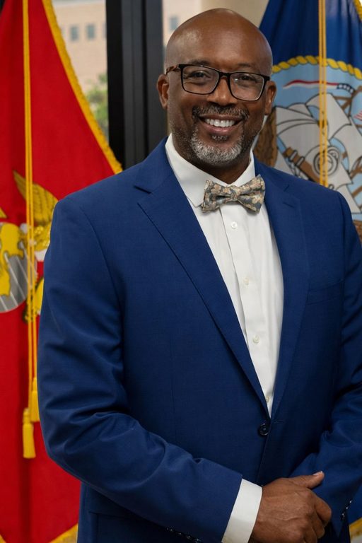 Man in blue suit with bow tie smiling.