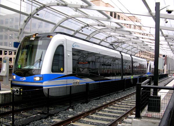 A blue-and-white LYNX light rail train at a covered station platform.