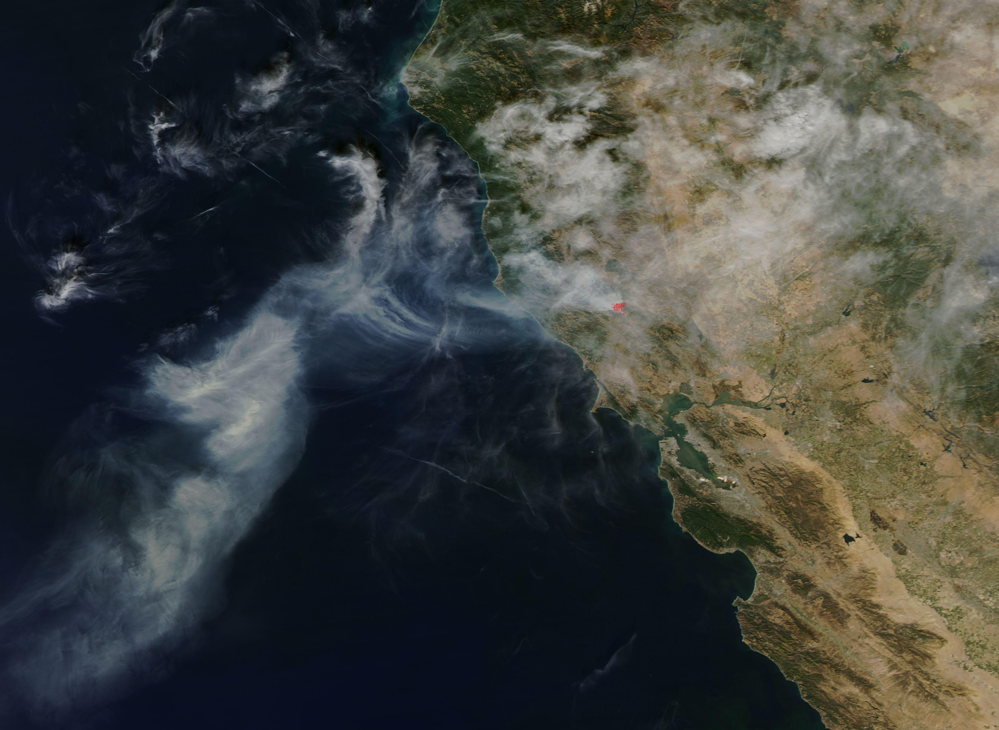 Satellite view of California coastline with large wildfire smoke plumes over the ocean.