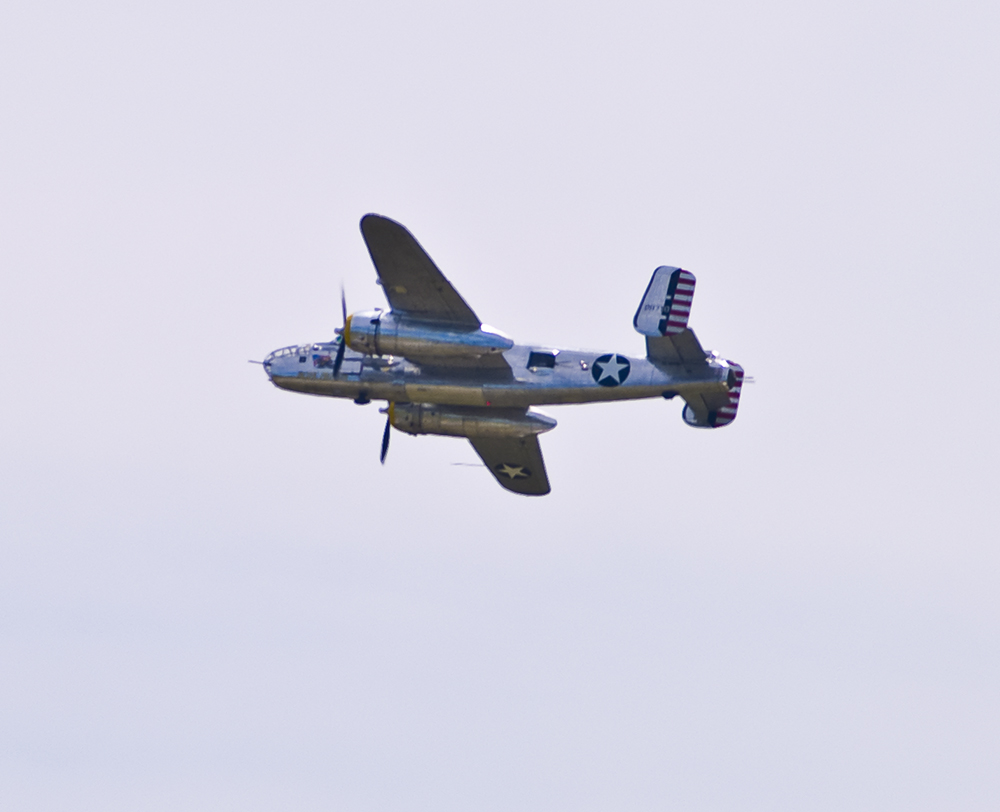 Twin-engine World War II B-25 Mitchell bomber in flight, showing U.S. military markings.