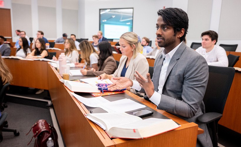 Students seated at tiered desks in a modern law school classroom.