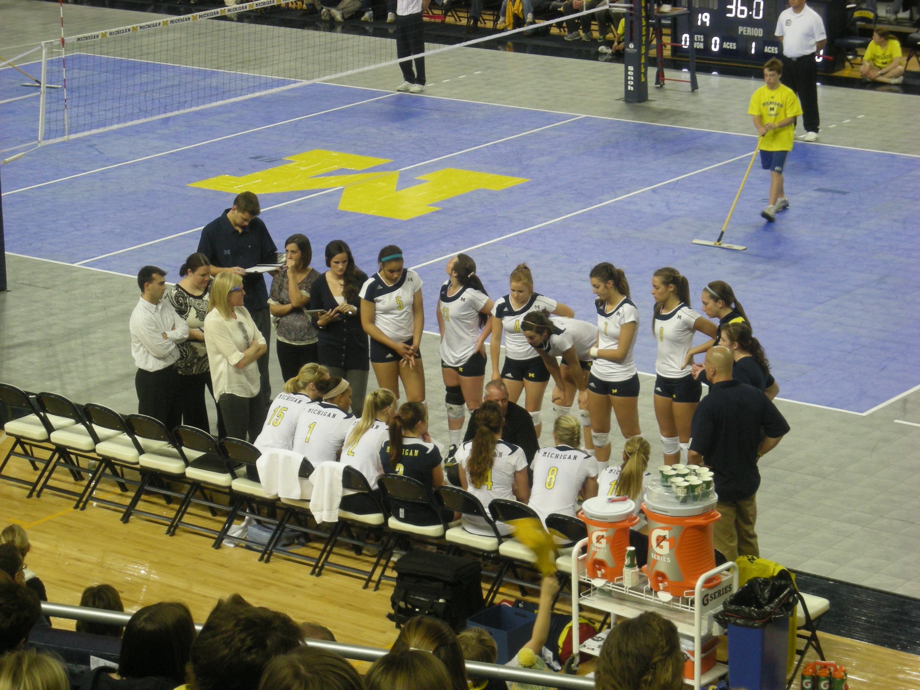 Michigan volleyball players and coaches huddle during a timeout at Crisler Arena.