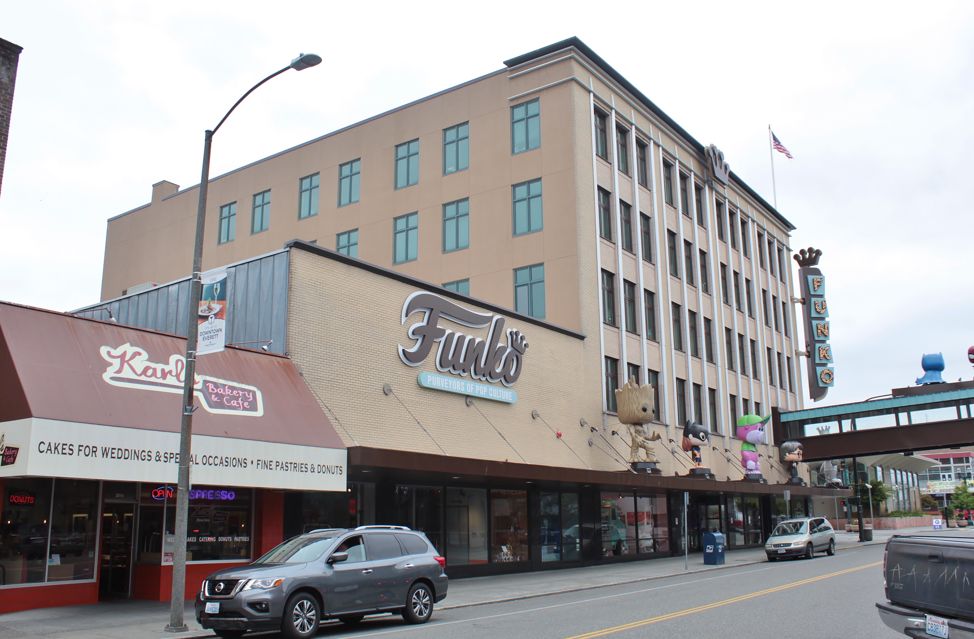 Multi-story building with large Funko logo on facade, parked cars on street below.