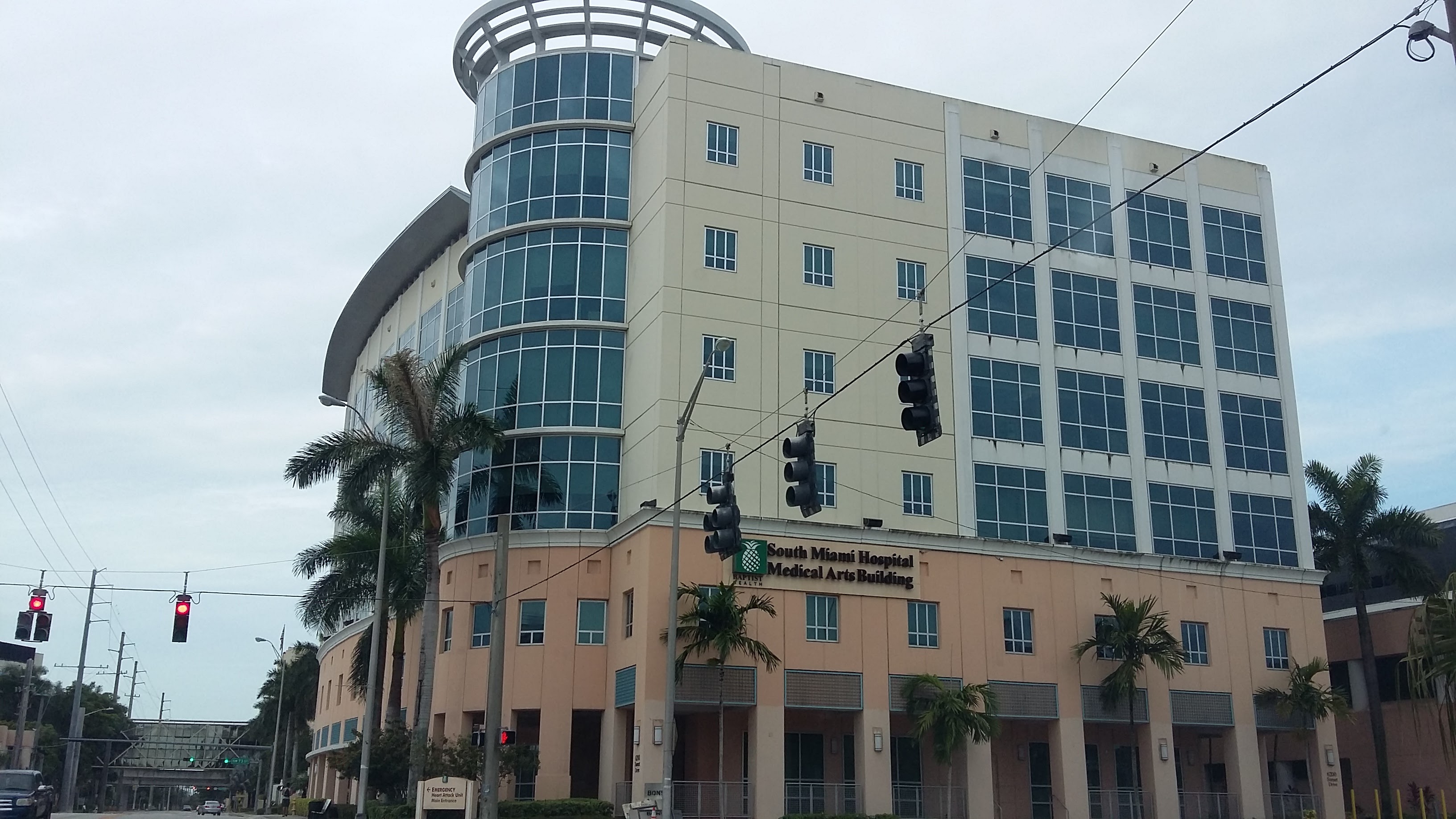 Multi-story glass-facade medical office building with palm trees at a street intersection