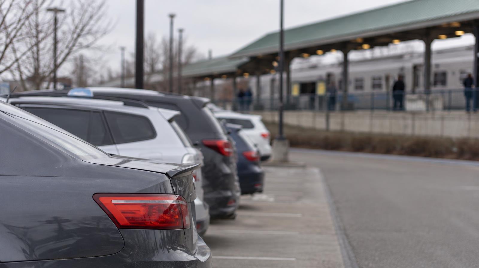 Surface parking lot with a transit station canopy visible in the background.