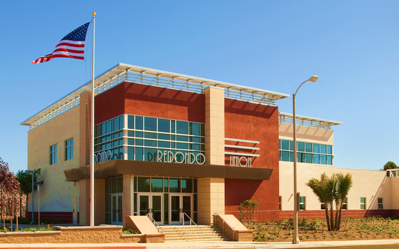 Modern two-story school building with red walls and the word REDONDO on the facade.
