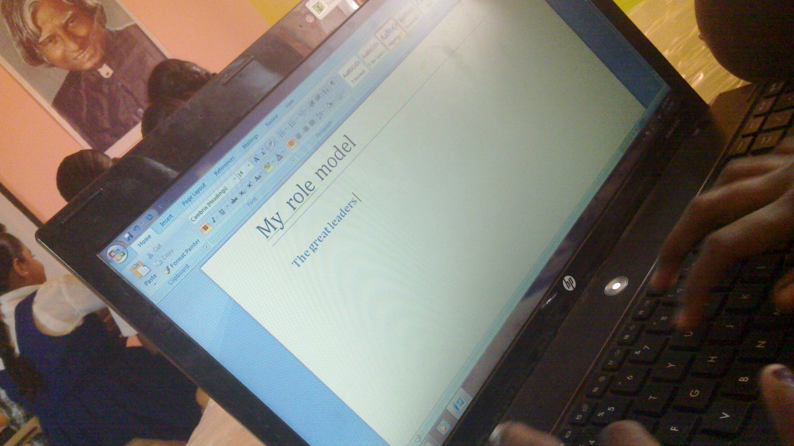 Close-up of a student's hands typing on a laptop in a school setting.