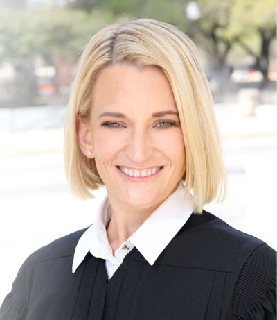 Portrait of a smiling woman with short blonde hair in a black robe.