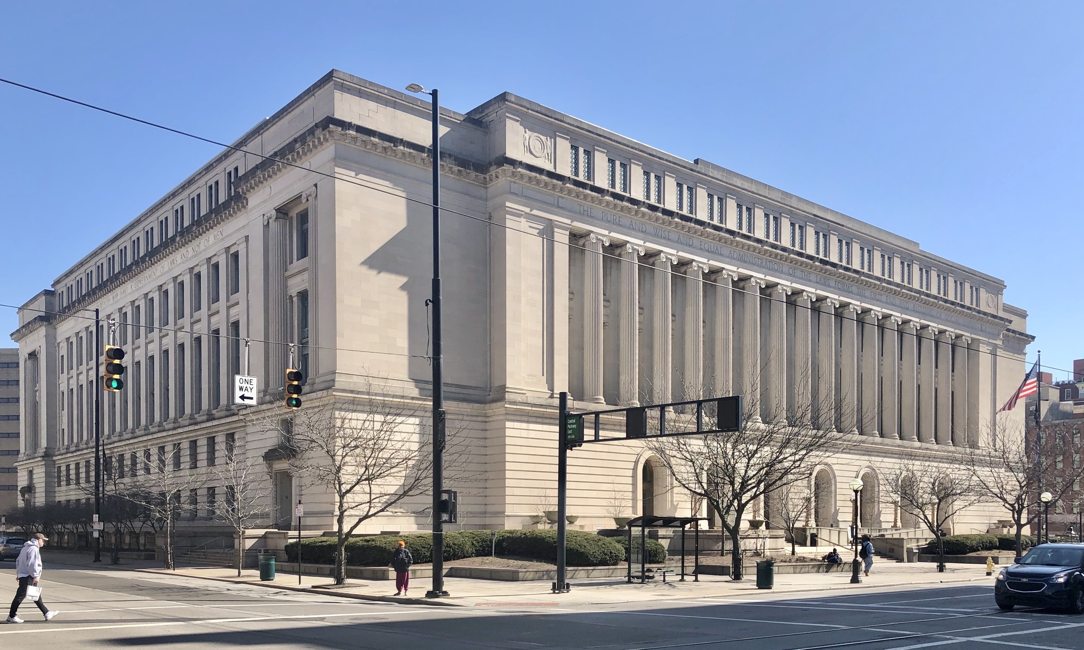 Large neoclassical government building with columns and an American flag on a clear day.