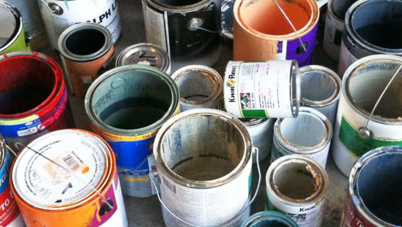 Numerous open and closed paint cans of various sizes showing dried paint residue inside.