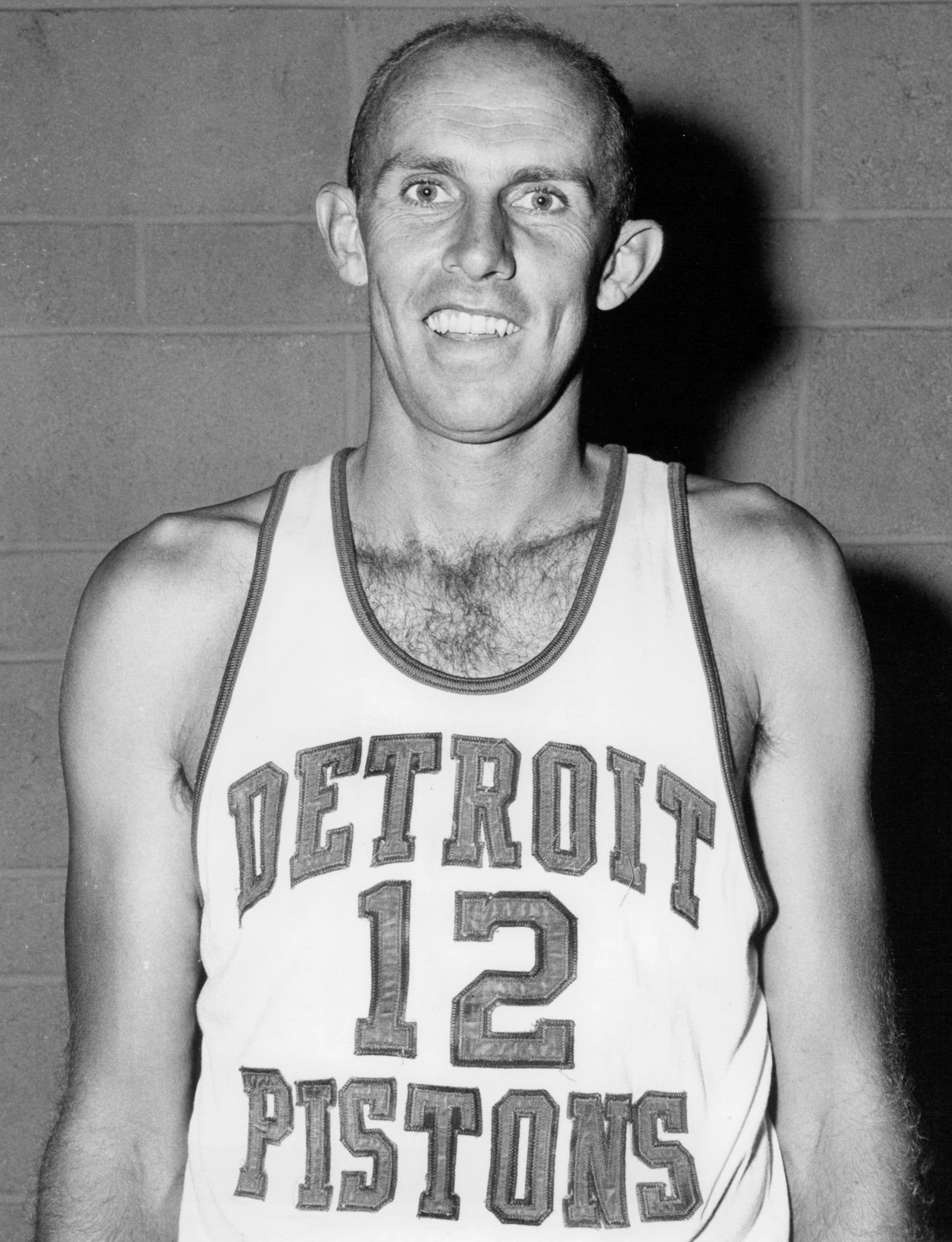Basketball player in uniform posed with a ball in a mid-20th century black-and-white photo.