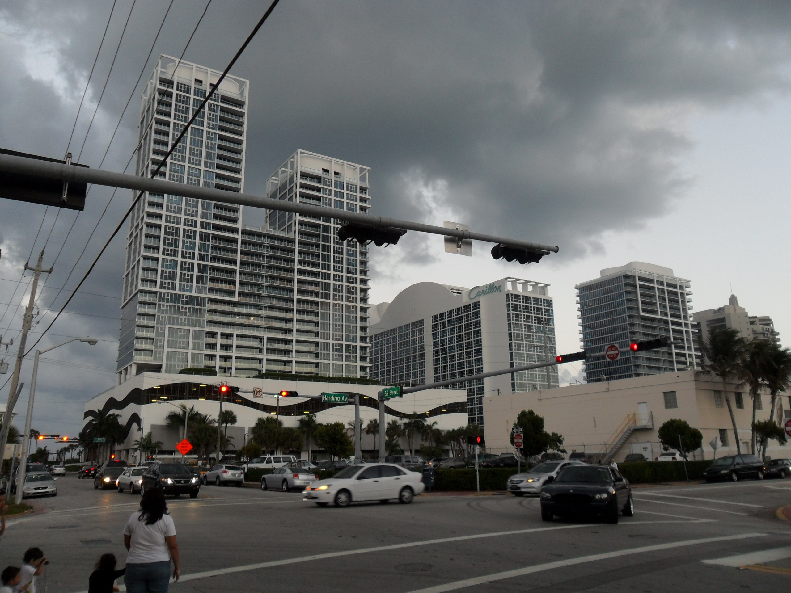 Tall condominium towers and palm trees line a busy Miami Beach street intersection.