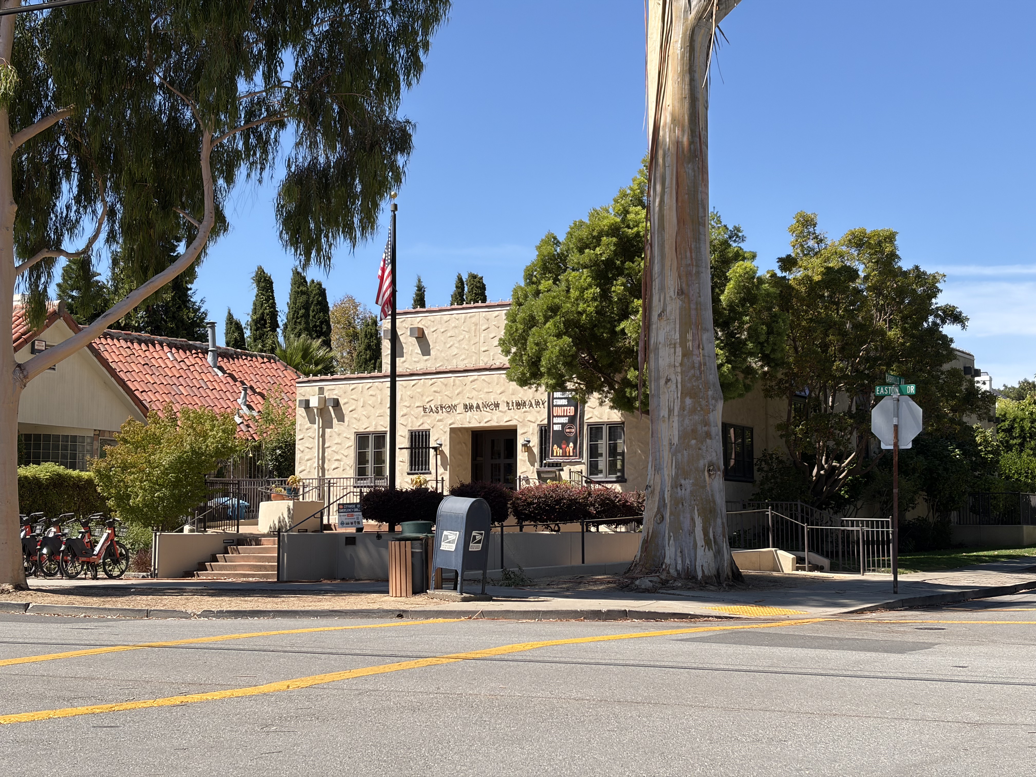 Single-story stone-faced library building with red-tile roof and flagpole out front.