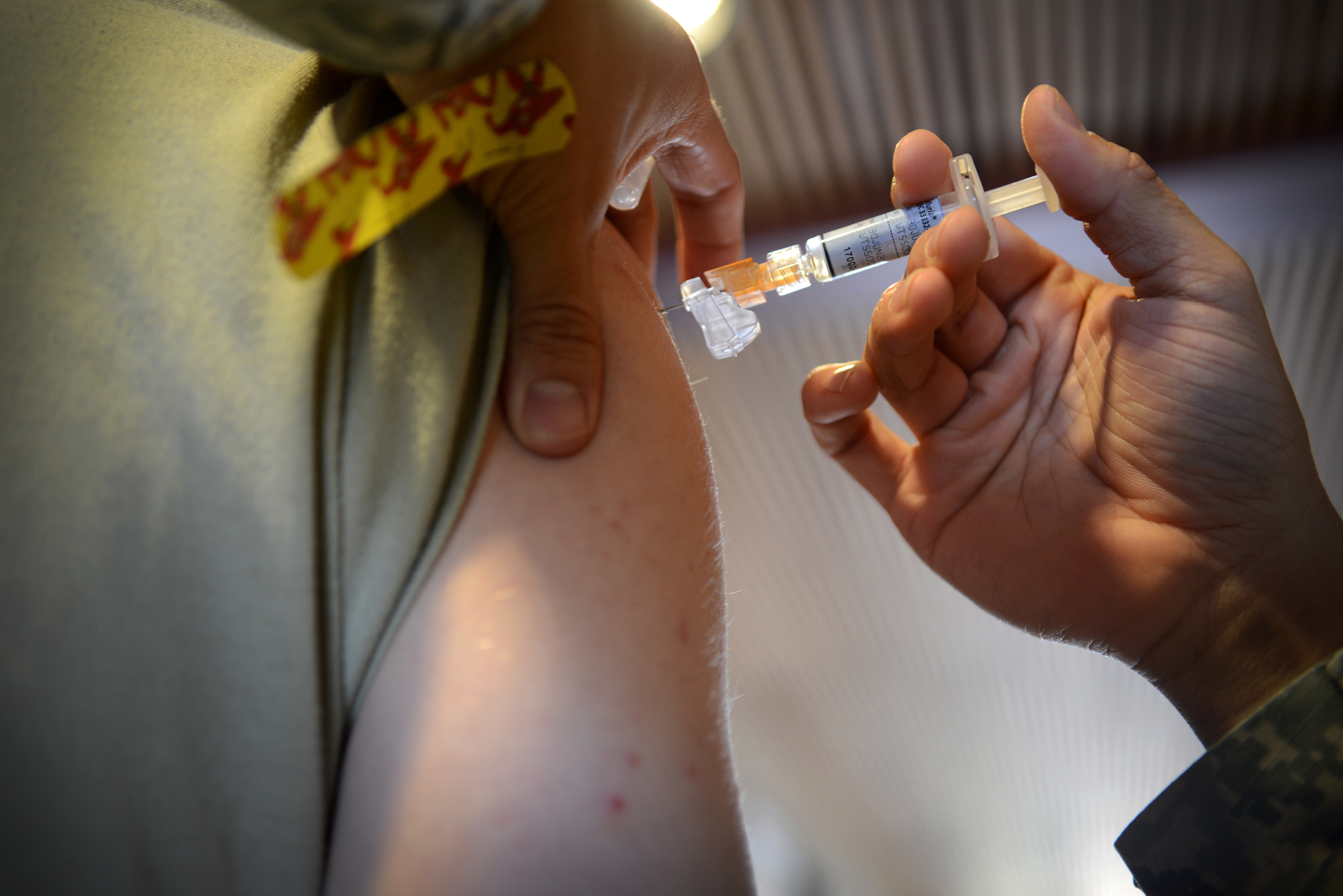 A healthcare worker administers a flu shot into a patient's upper arm.