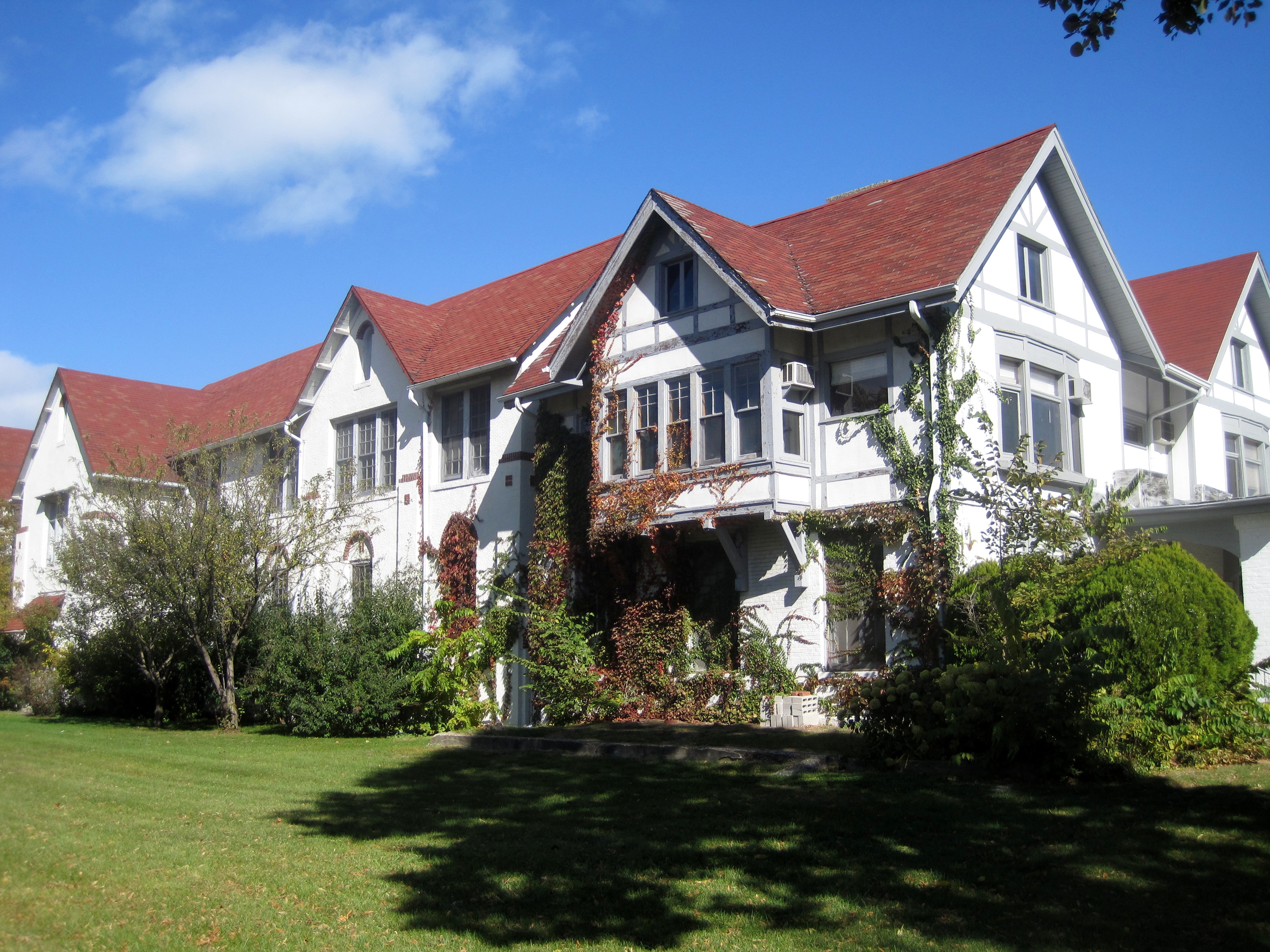 Large white Tudor-style school building with red roofs and gabled dormers on a green lawn