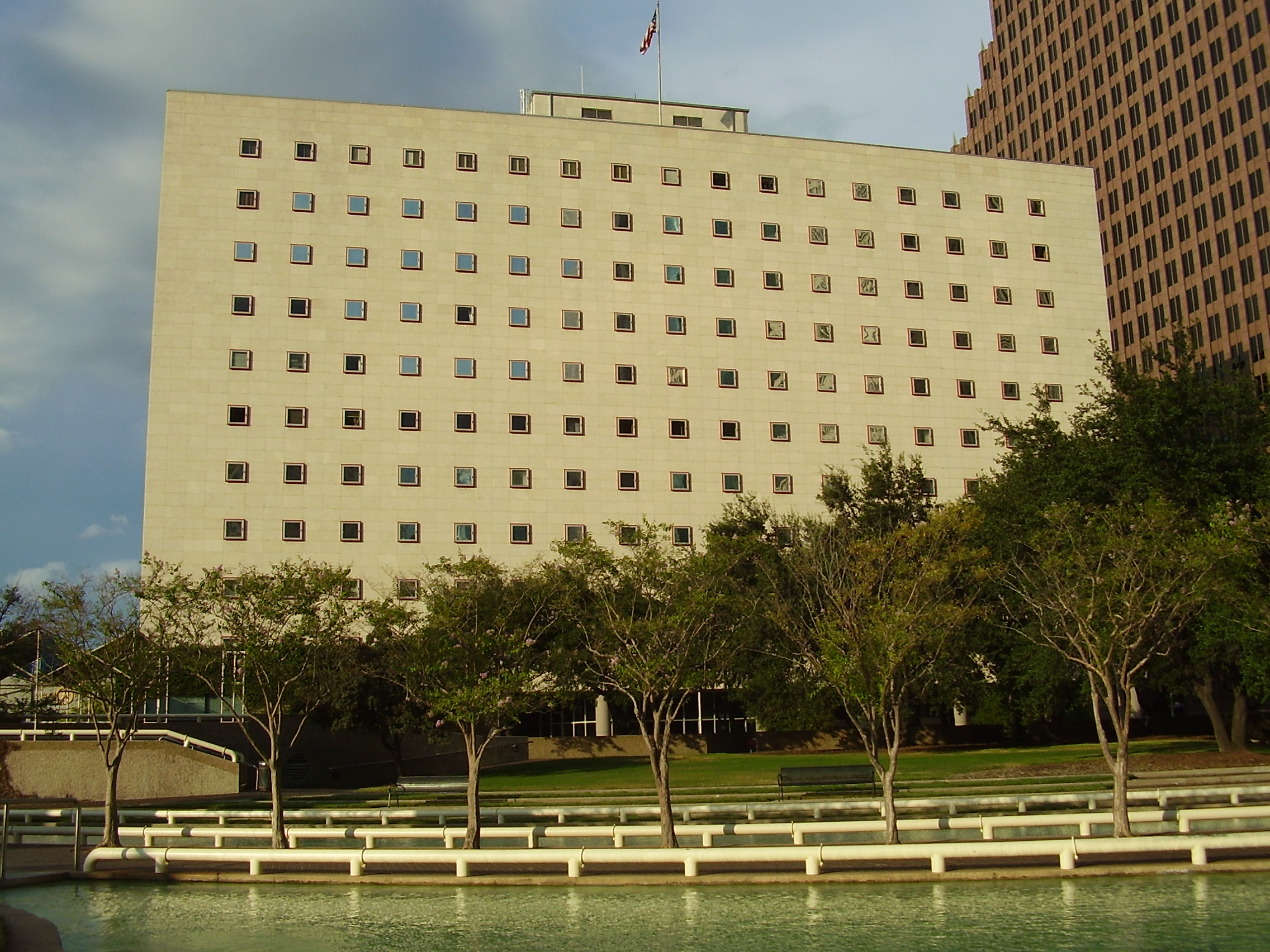 Multi-story federal courthouse building with square windows, trees, and a reflecting pool in front.