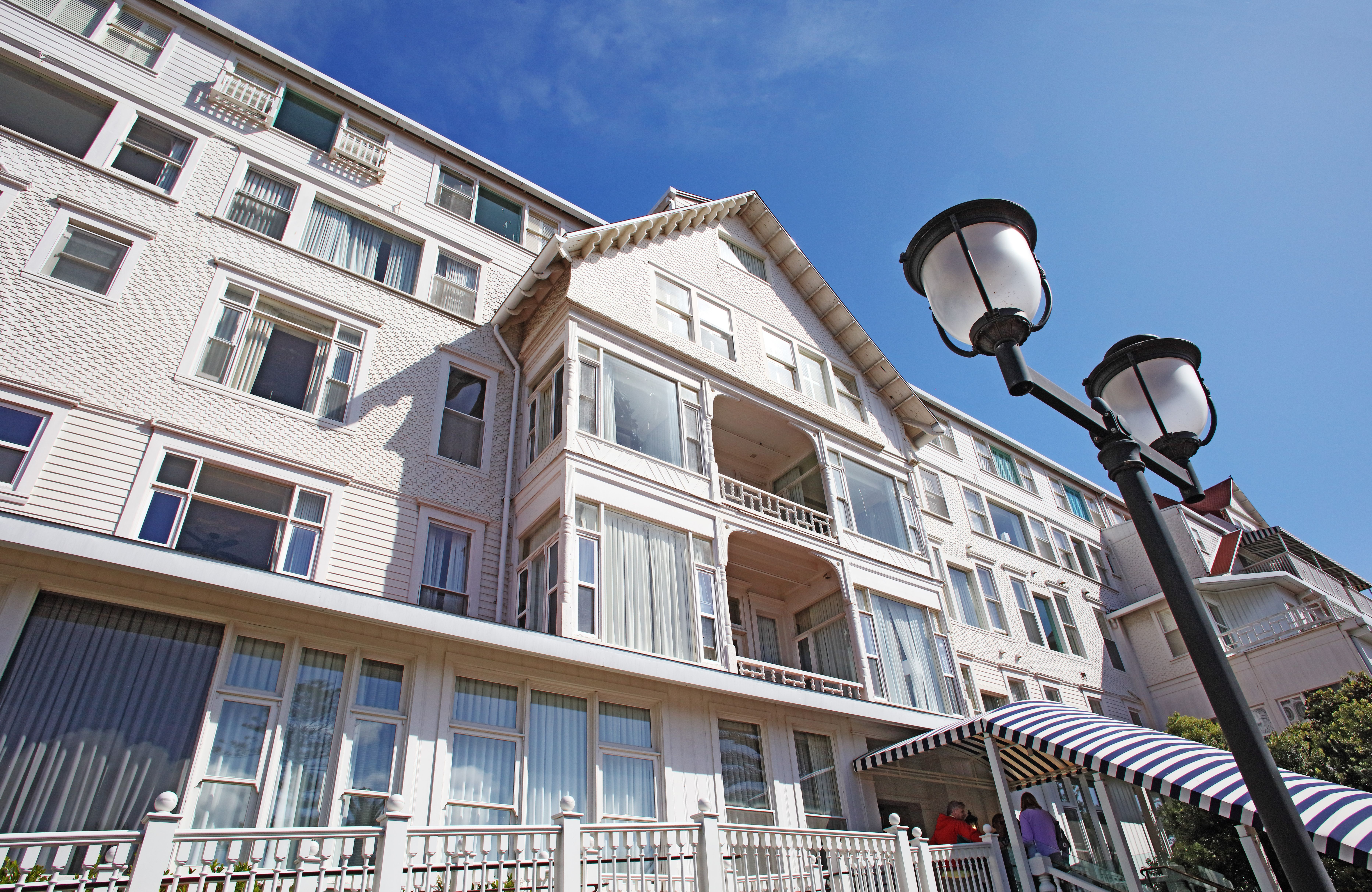 White Victorian hotel exterior with balconies, ornate trim, and a black street lamp.