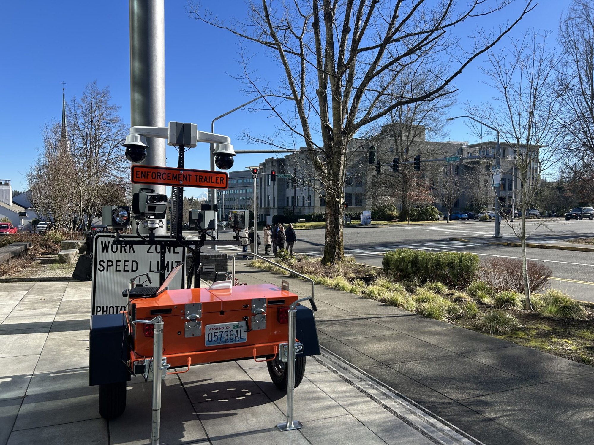 An orange trailer-mounted speed enforcement camera with cameras on top and work zone speed limit signage.