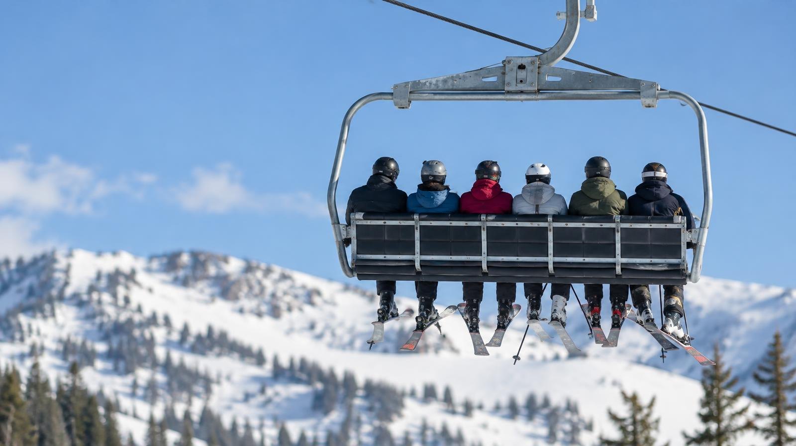 A six-person ski chairlift chair suspended from a cable against a blue winter sky.