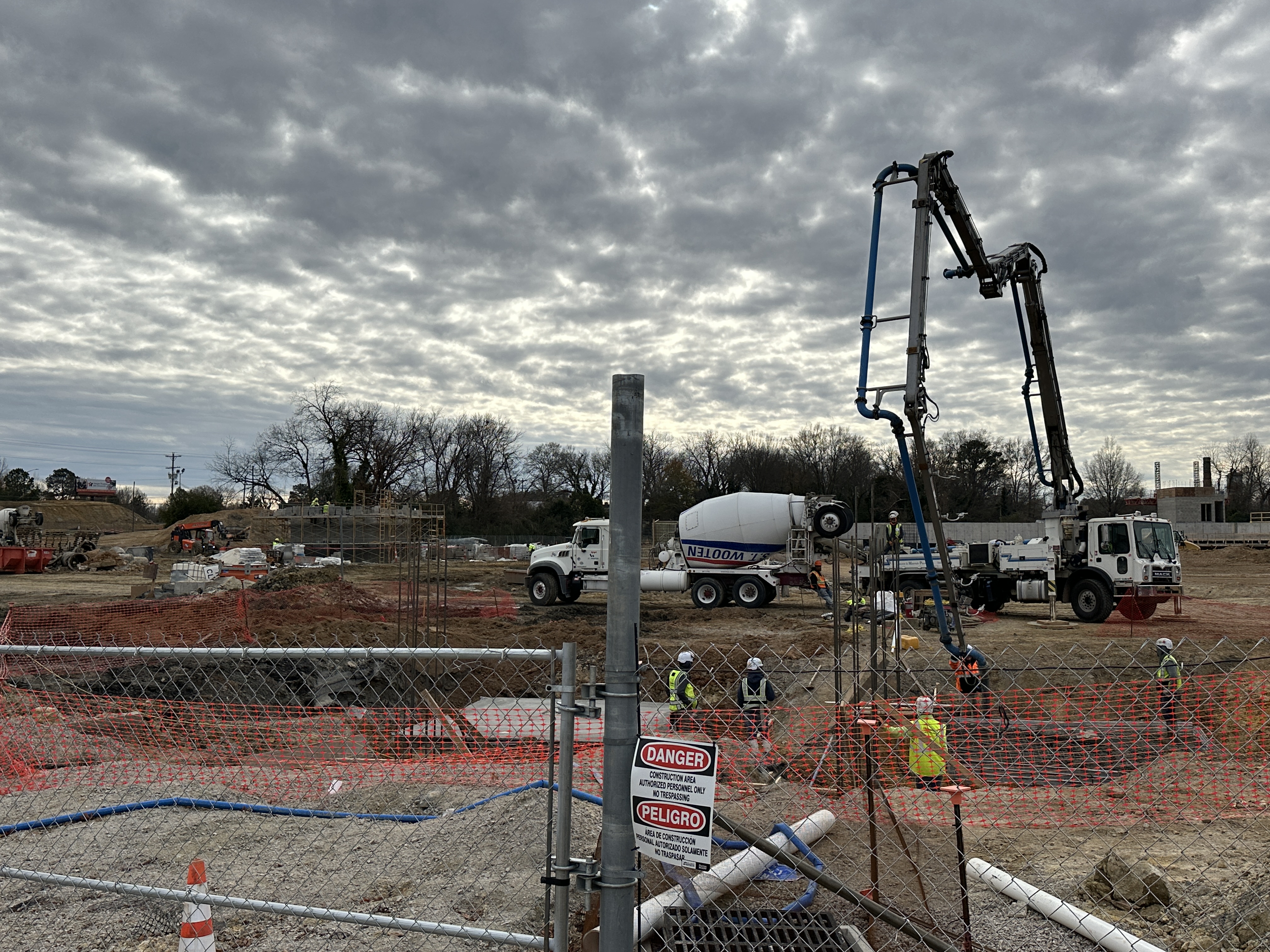 Concrete pump truck and workers in safety vests at an active construction site with rebar.