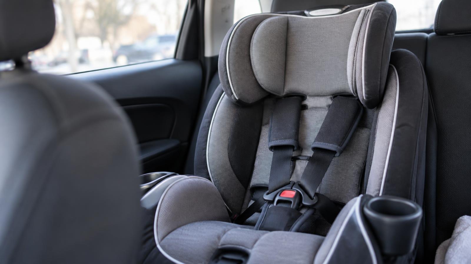 A child's forward-facing car seat with harness straps secured in a vehicle back seat.