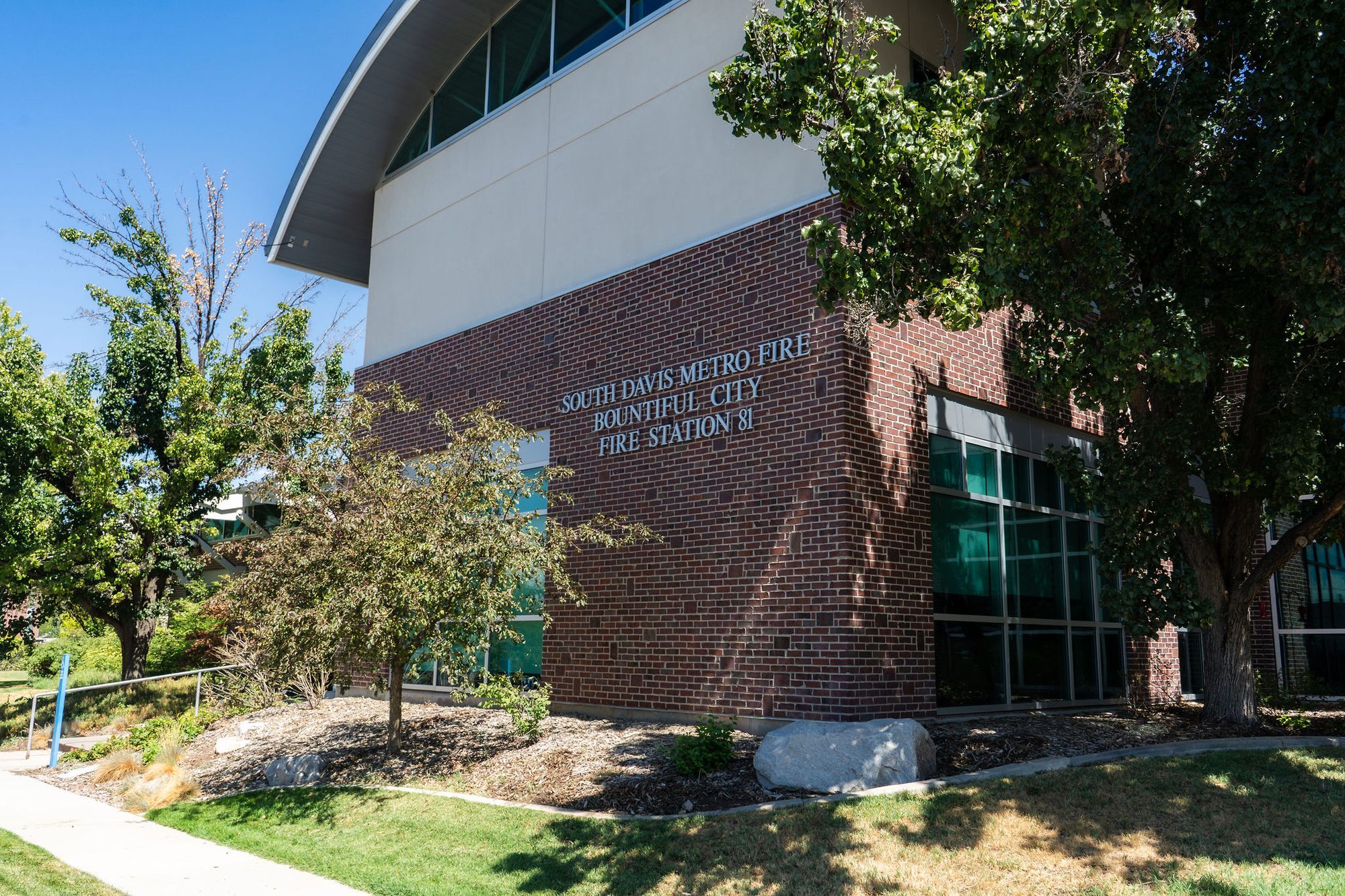 Brick fire station exterior with large windows and silver lettering on the wall.