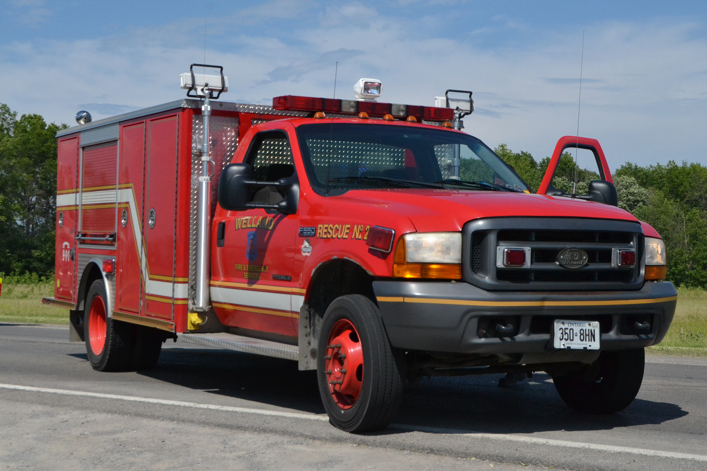 A red fire department rescue truck parked on a road at an accident scene.