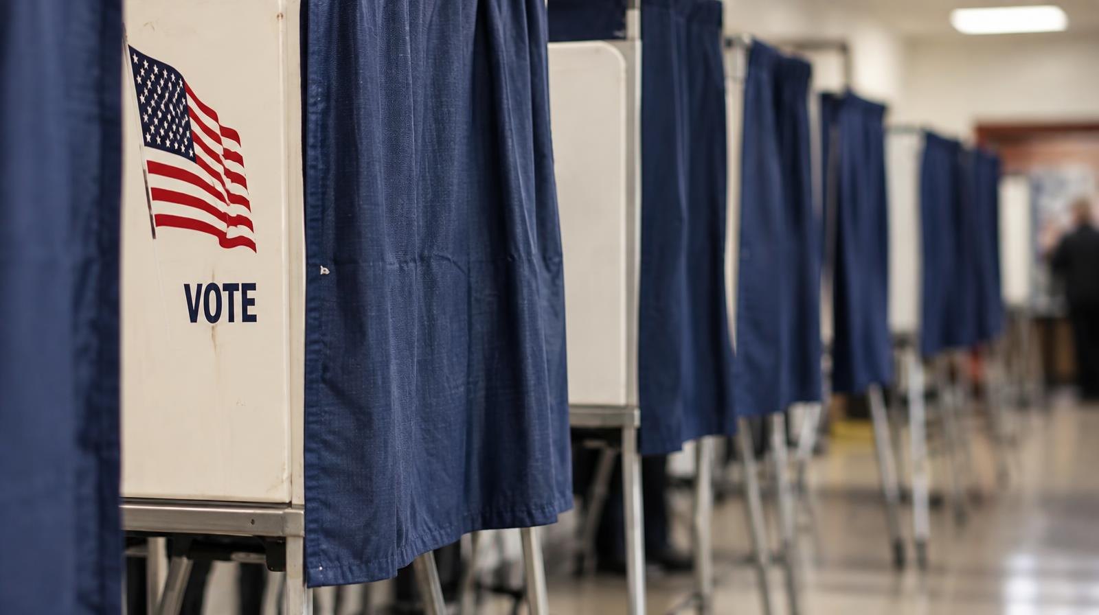 A row of voting booths with privacy curtains inside a polling place.
