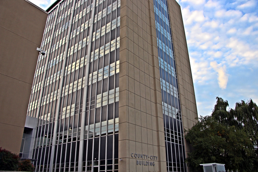 Multi-story tan office building labeled County-City Building against a partly cloudy sky.
