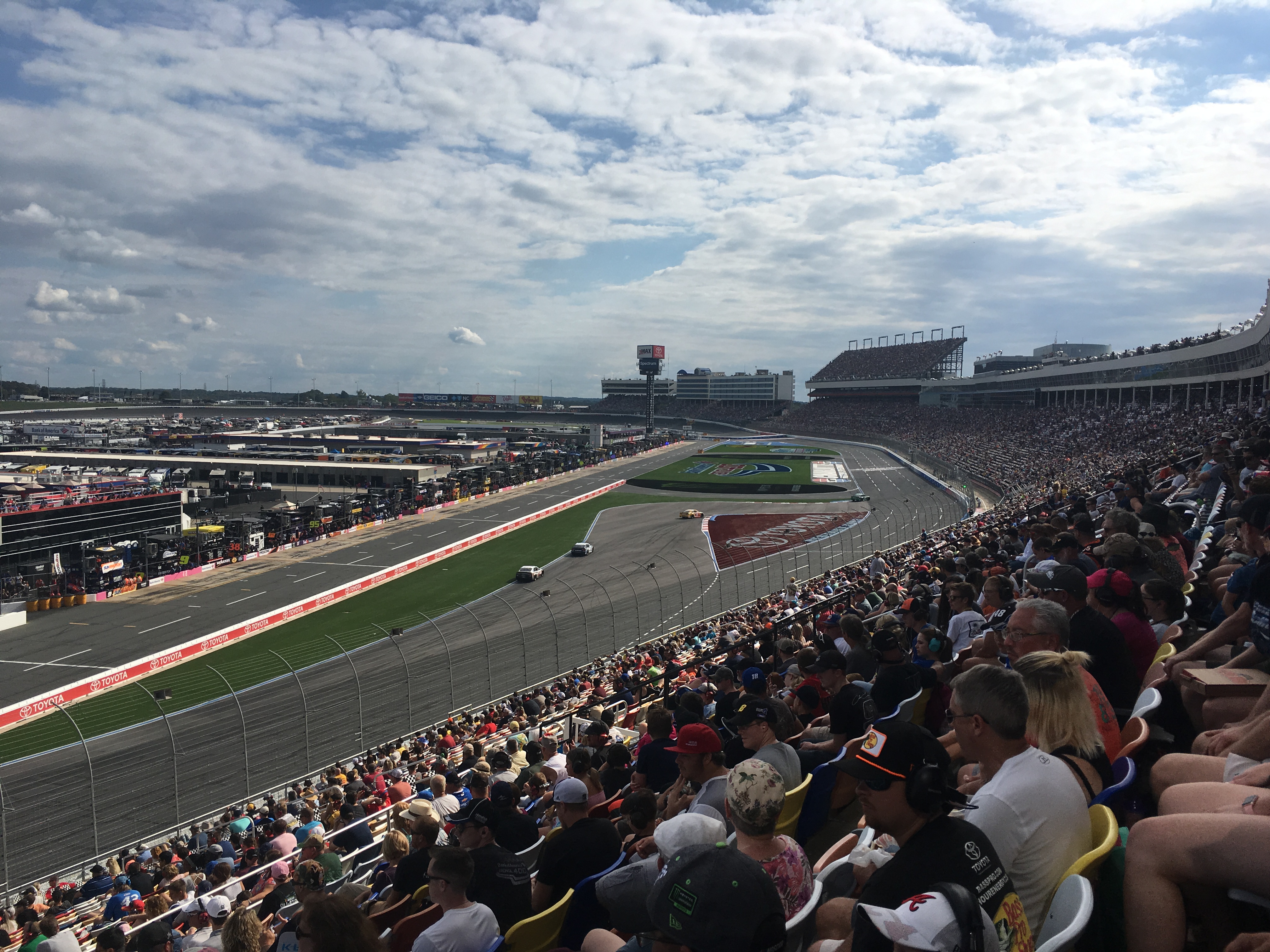 NASCAR race cars on track at Charlotte Motor Speedway with packed grandstands.