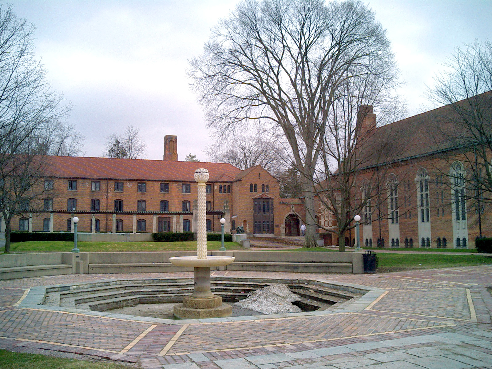 Stone fountain in a brick courtyard flanked by red-brick academic buildings.