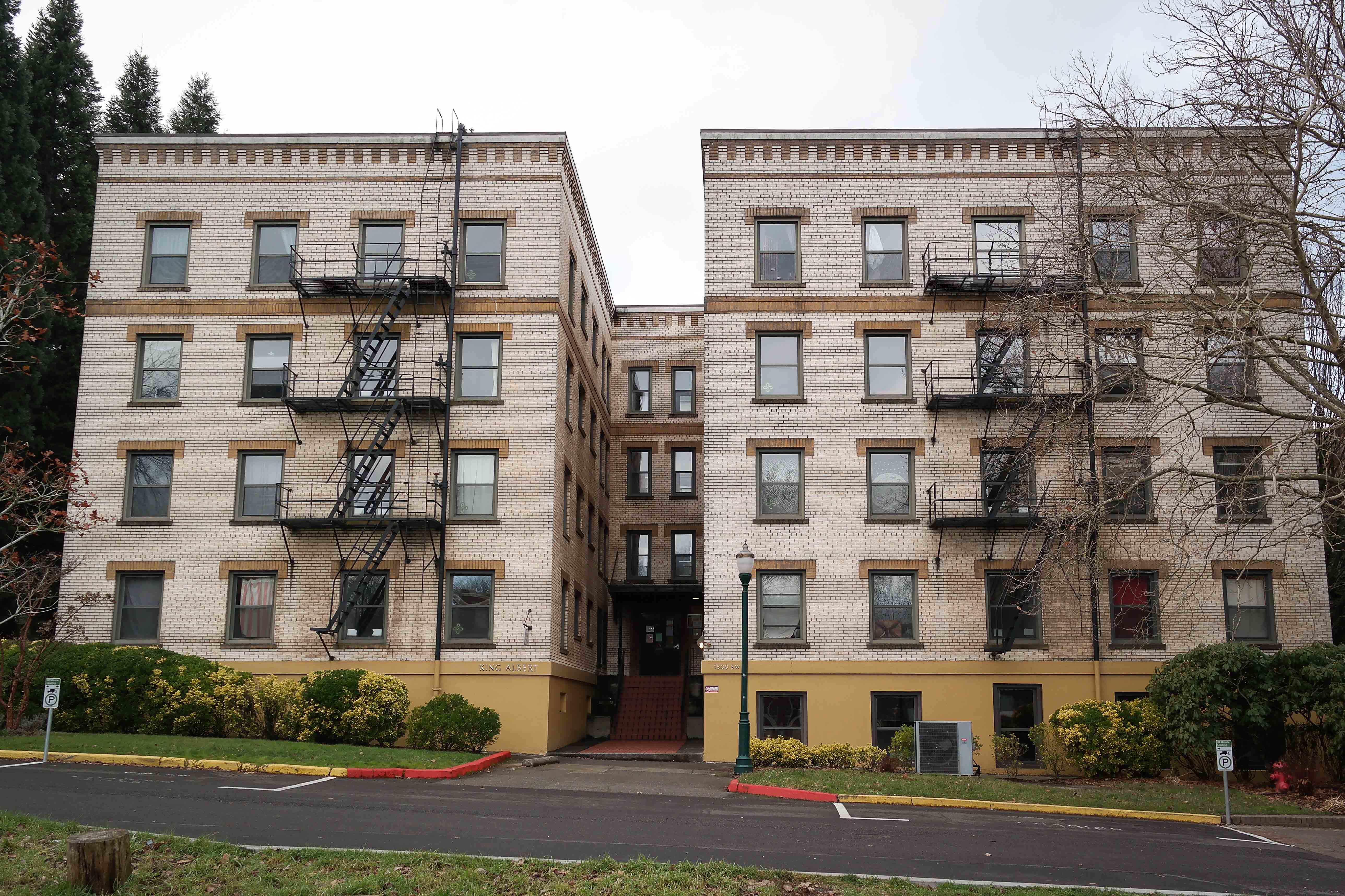 Four-story white brick building with black exterior fire escapes on a university campus.