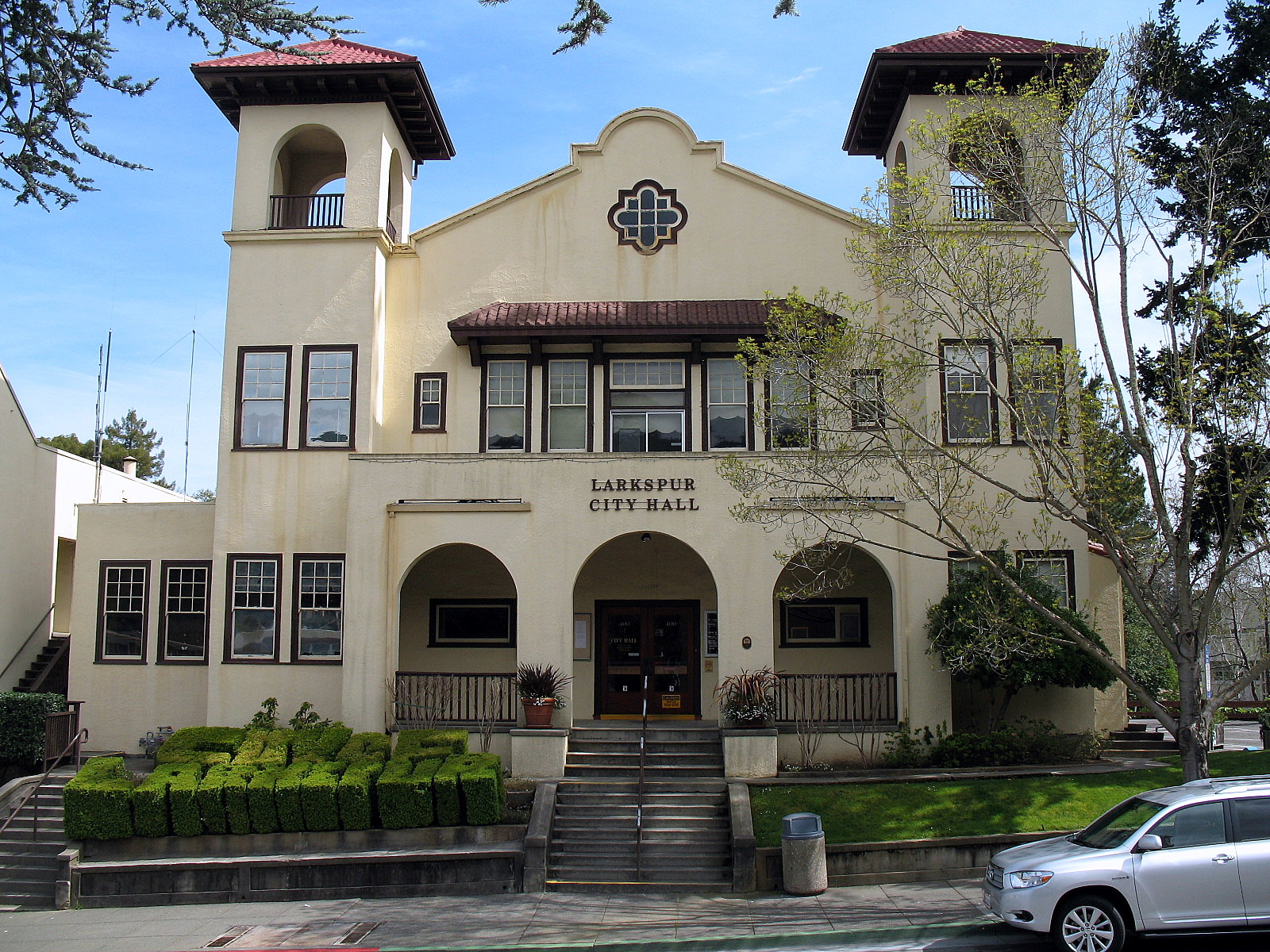 Mission Revival city hall with red tile roof, twin bell towers, and arched entryway