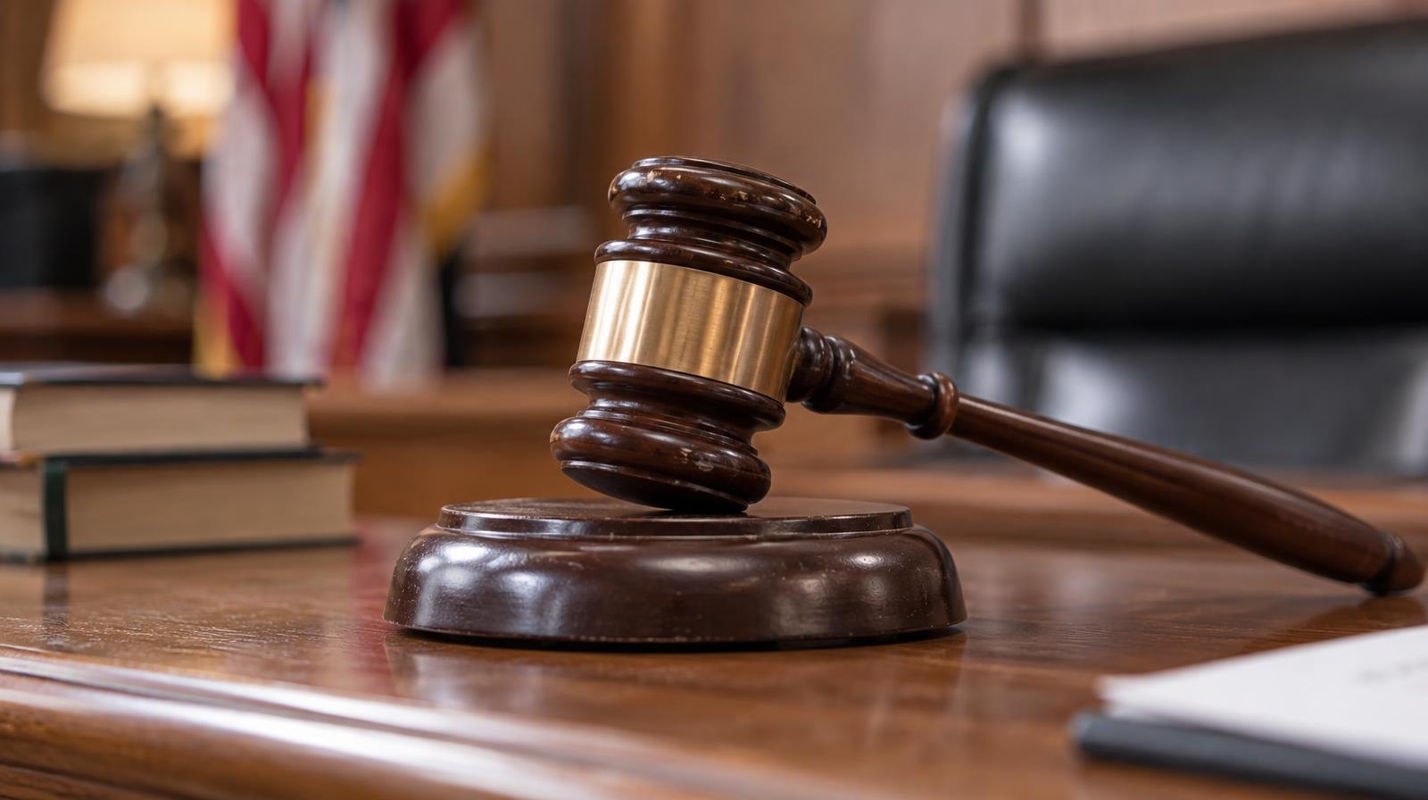 A wooden judge's gavel resting on its sound block on a bench.