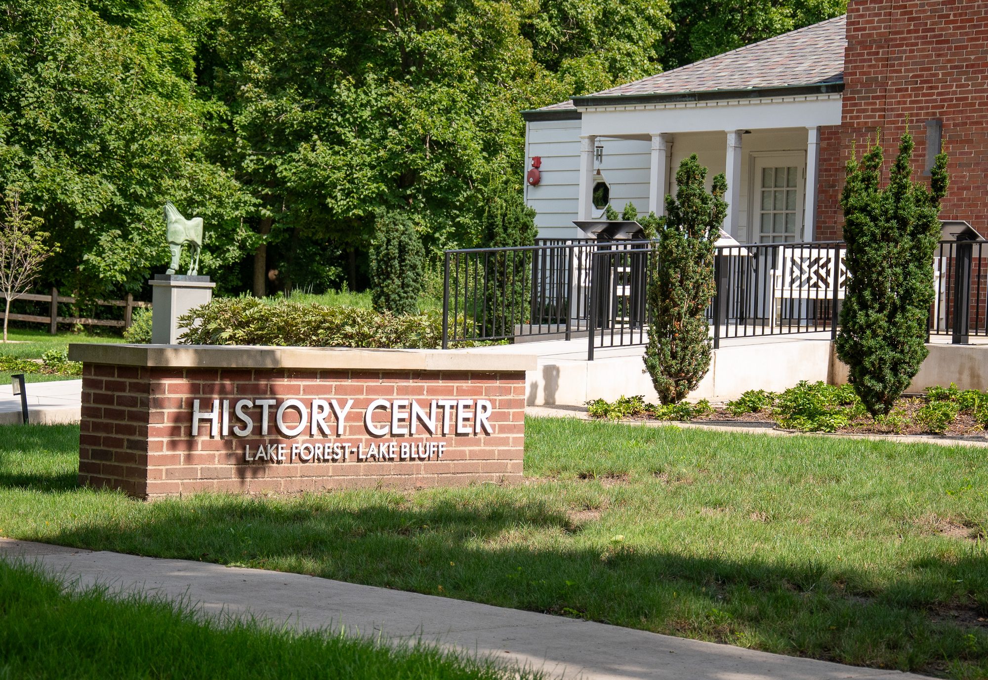 Brick monument sign for a history center in front of a white-columned building