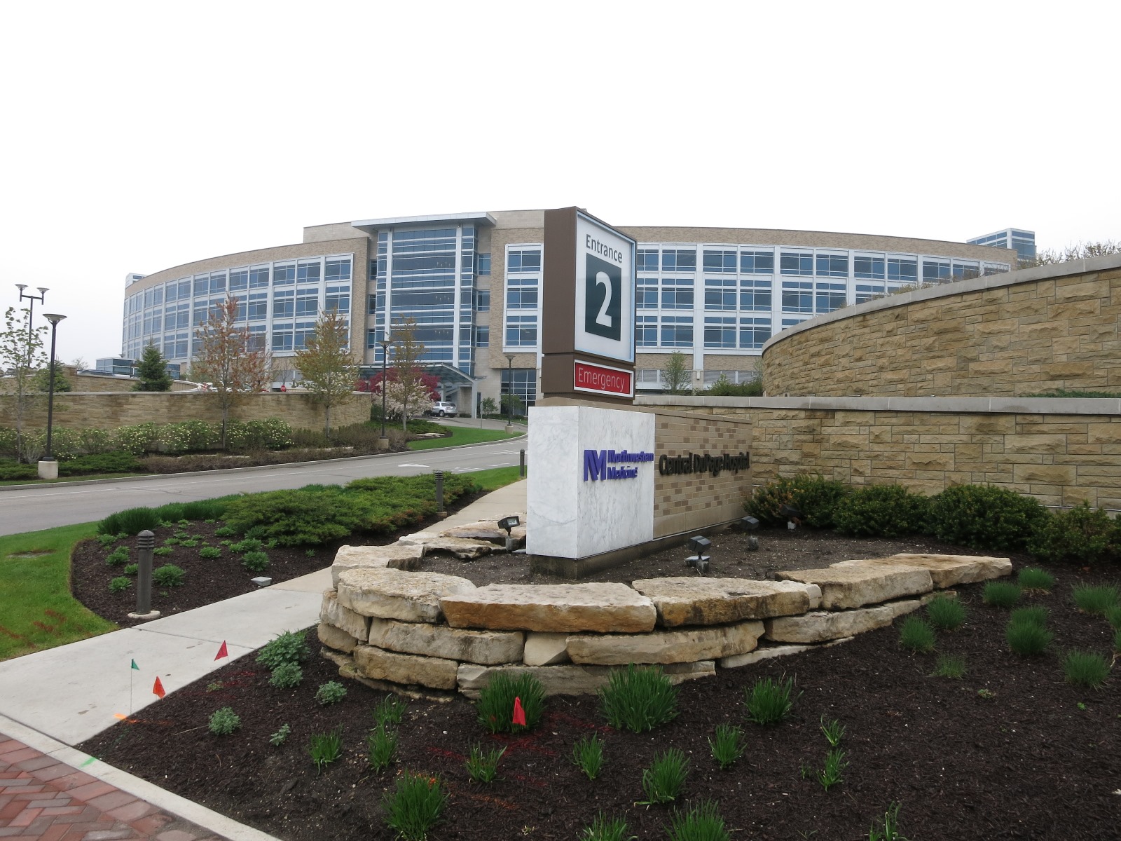 Exterior of a multi-story hospital building with a curved glass facade and entrance sign.