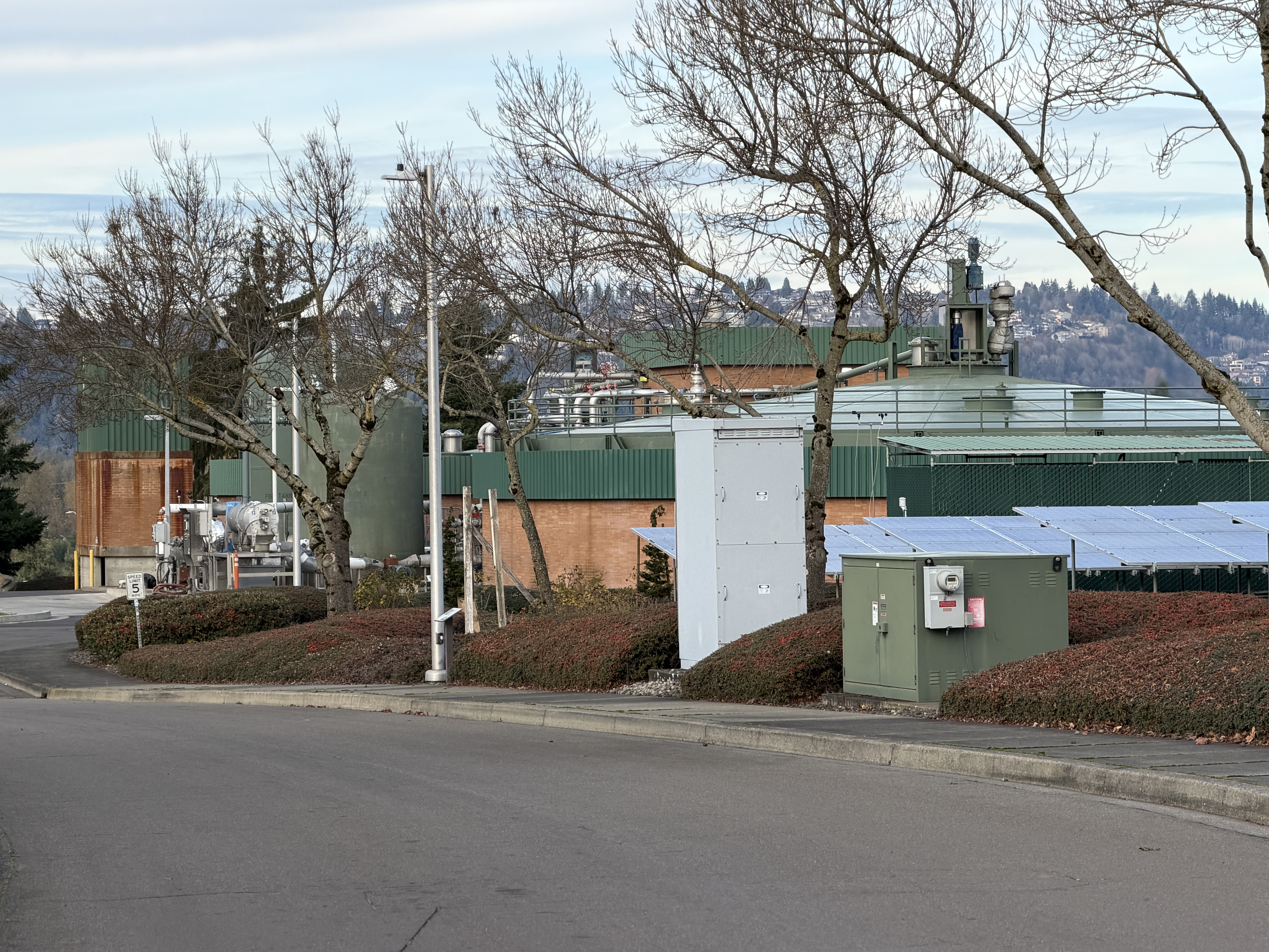 Green-roofed digester tanks and industrial buildings at a wastewater treatment plant.
