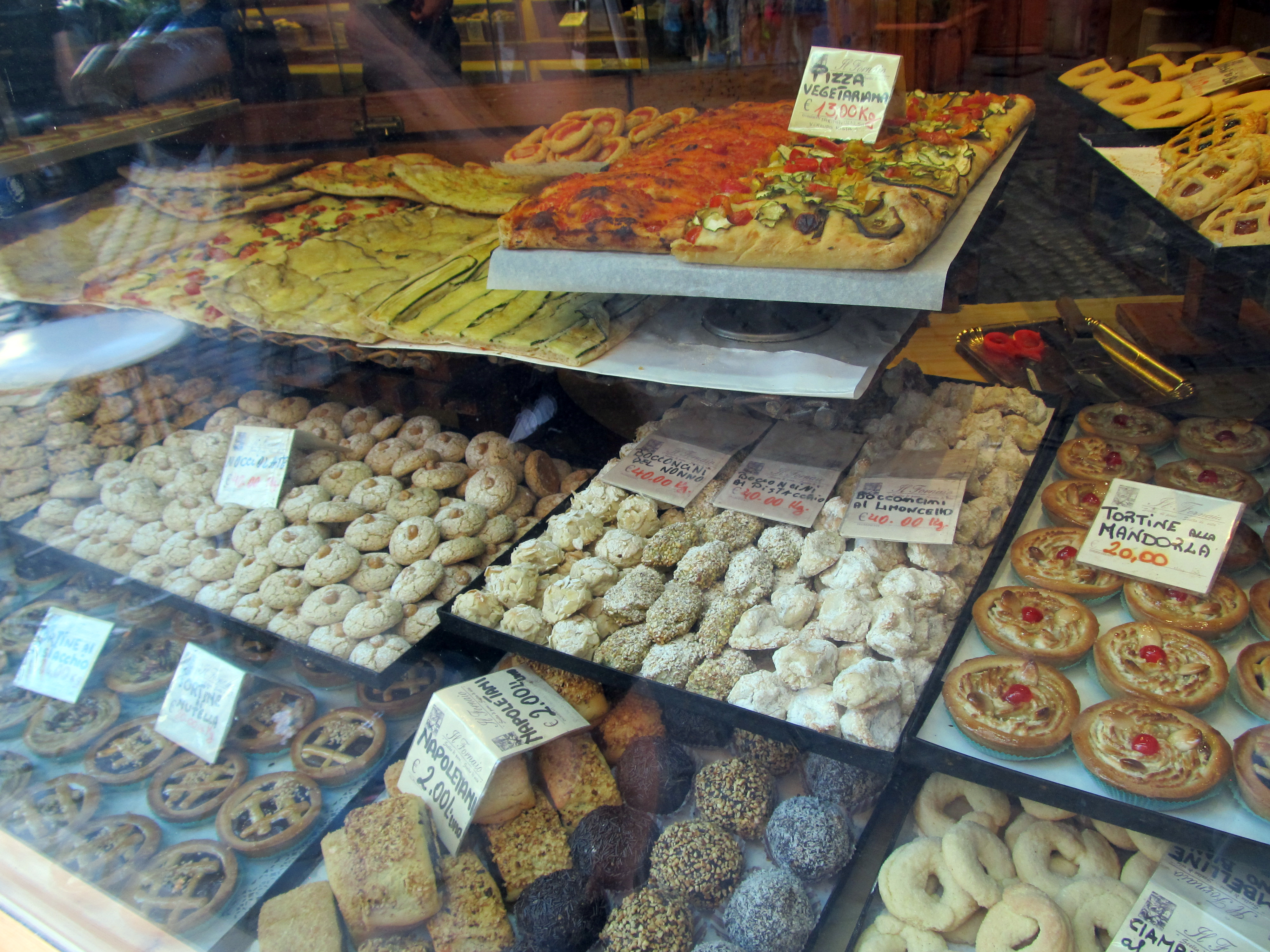 Glass display case filled with trays of assorted Italian cookies and pastries.