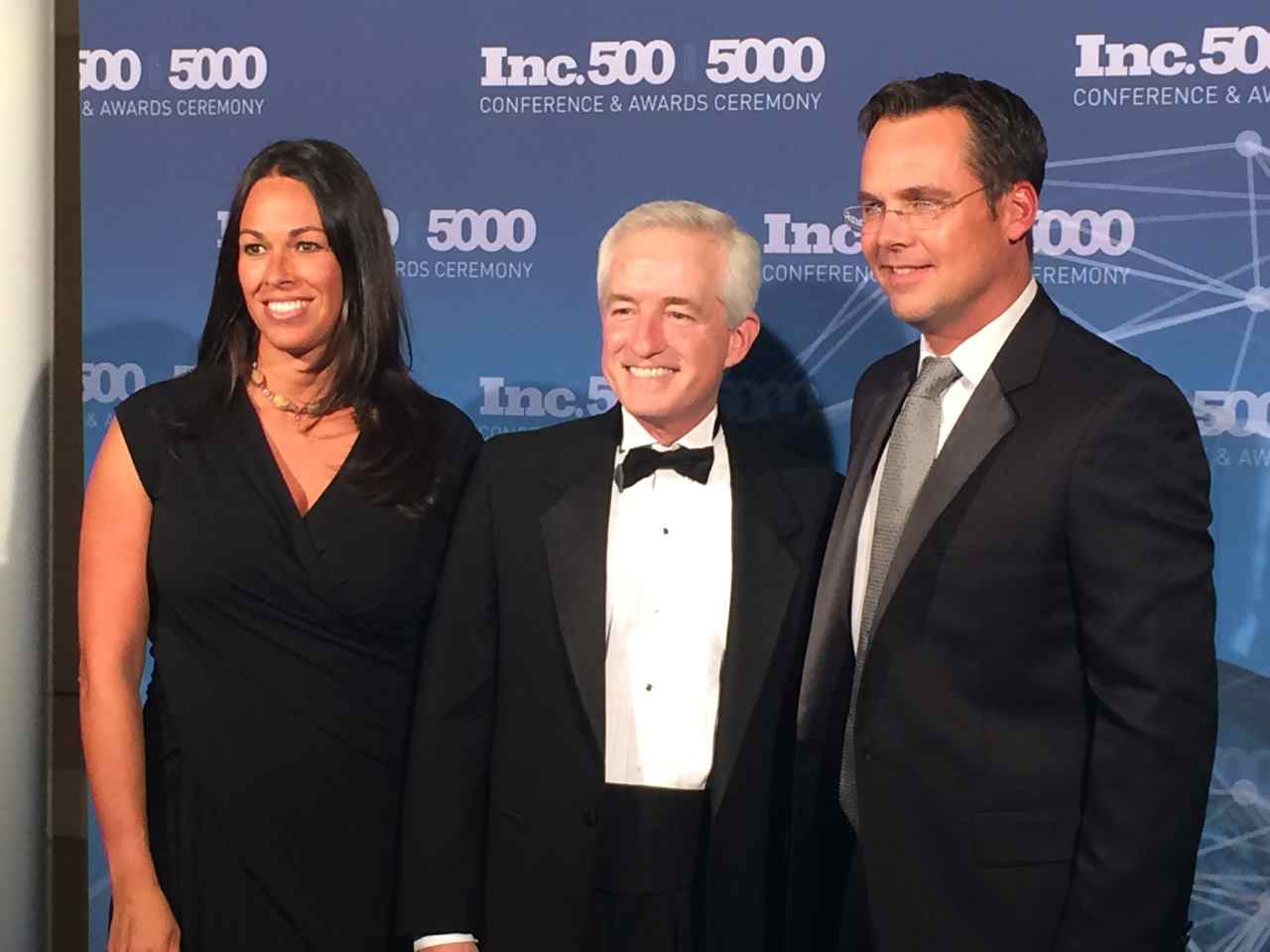 Three formally dressed attendees pose in front of an Inc. 500/5000 awards ceremony backdrop.