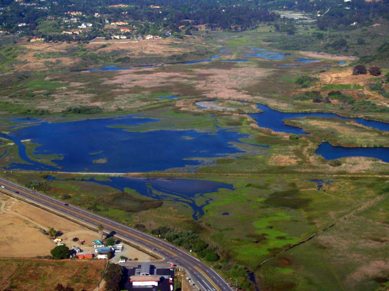 Aerial view of a coastal lagoon with open water channels and marsh vegetation in Southern California.