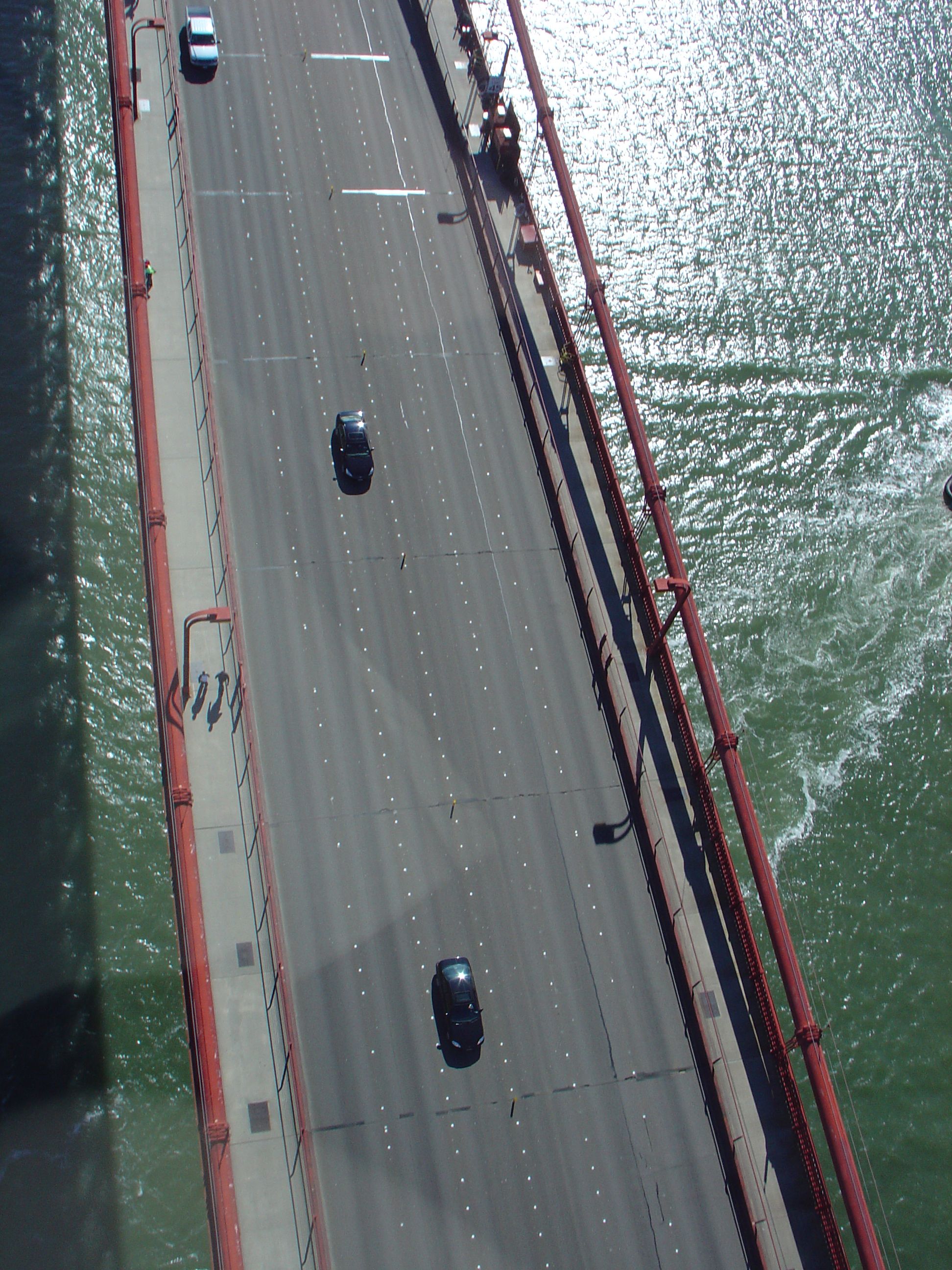Aerial view looking down at the Golden Gate Bridge roadway with multiple lanes of traffic.