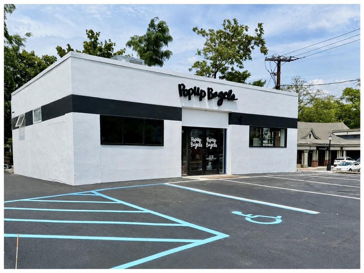 White single-story commercial building with PopUp Bagels signage and a freshly paved parking lot.