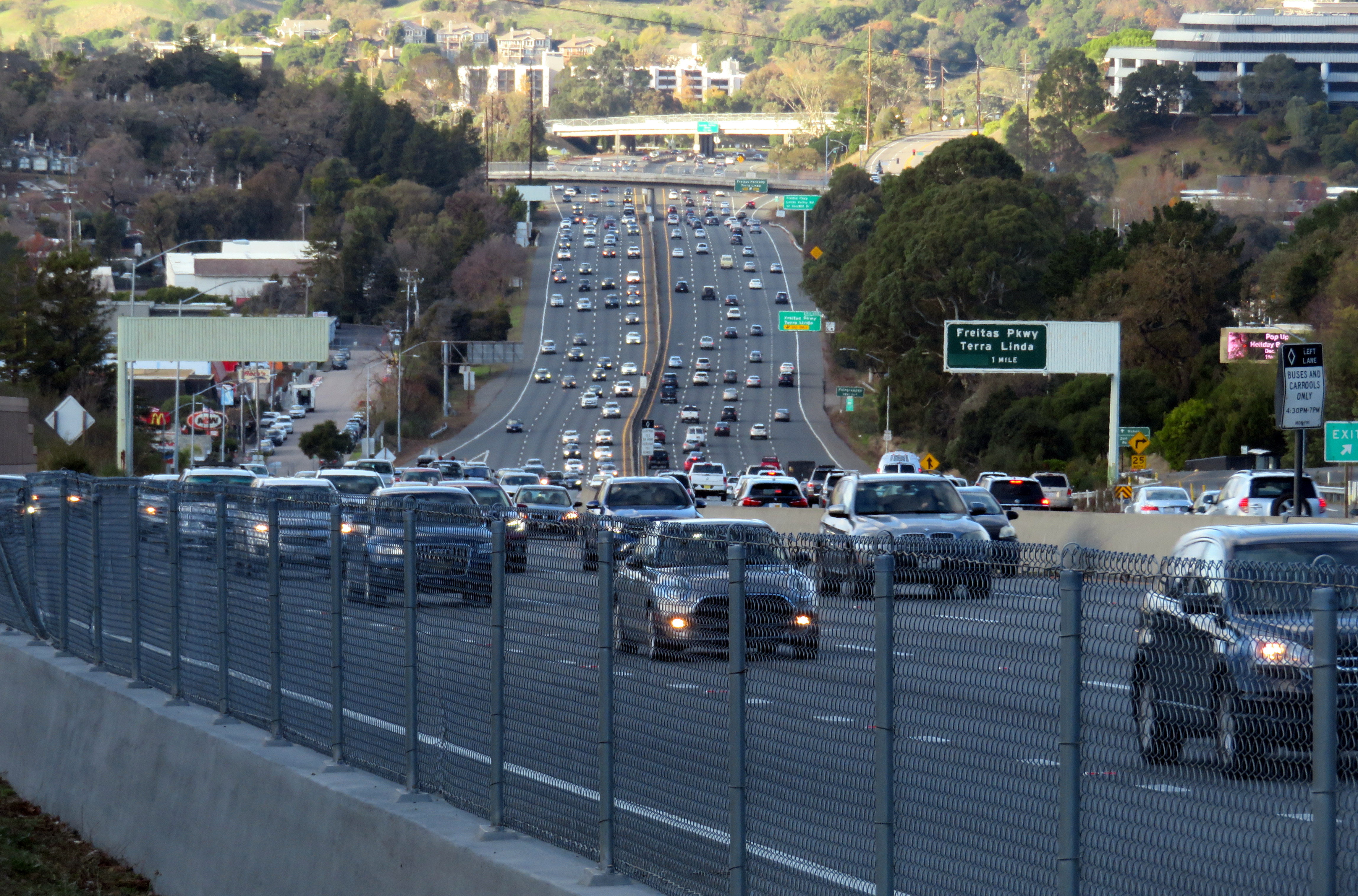 Multi-lane freeway with moving traffic and a green highway sign overhead
