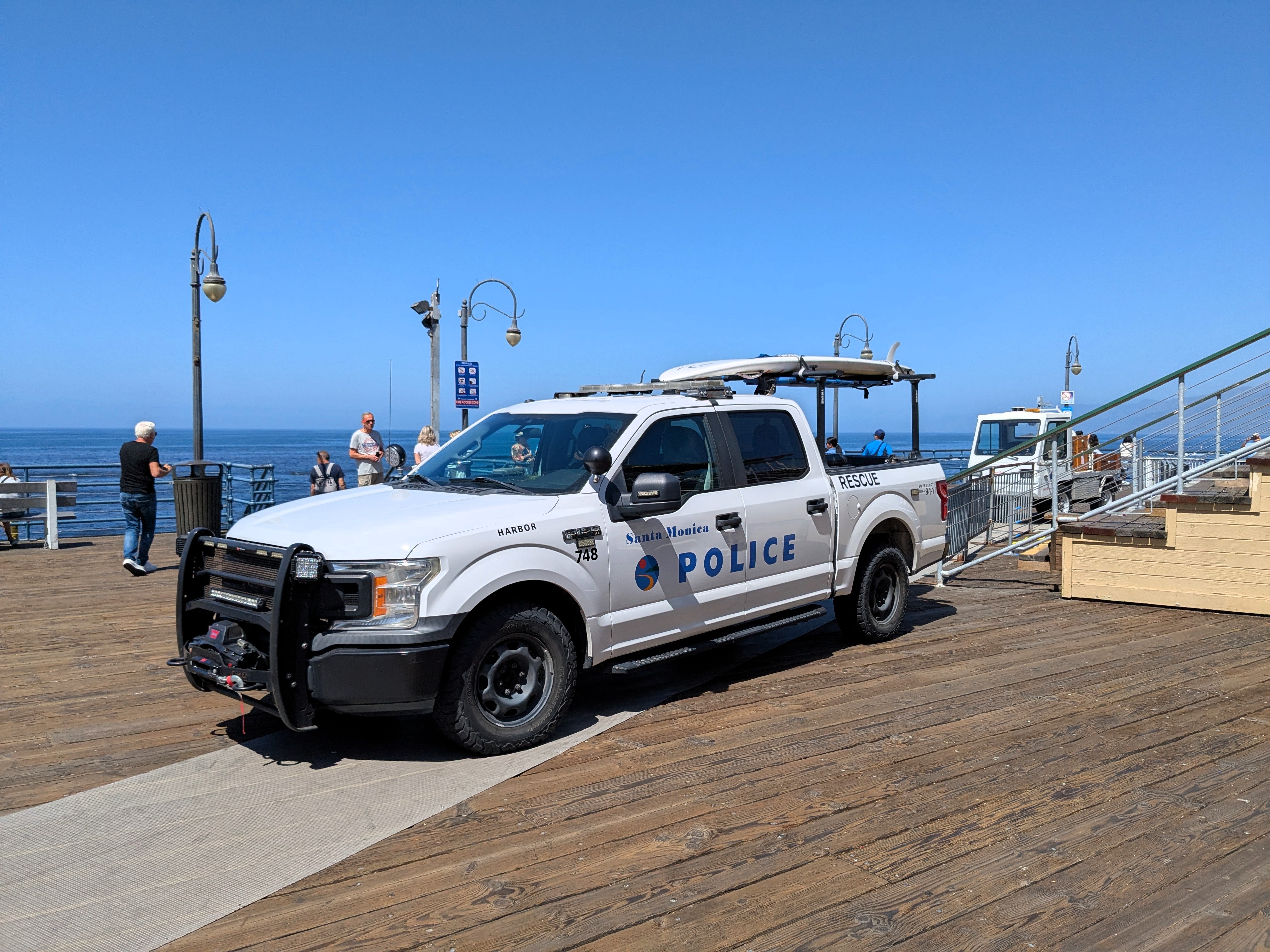 White Santa Monica Police pickup truck marked 'POLICE' and 'RESCUE' parked on a wooden pier.