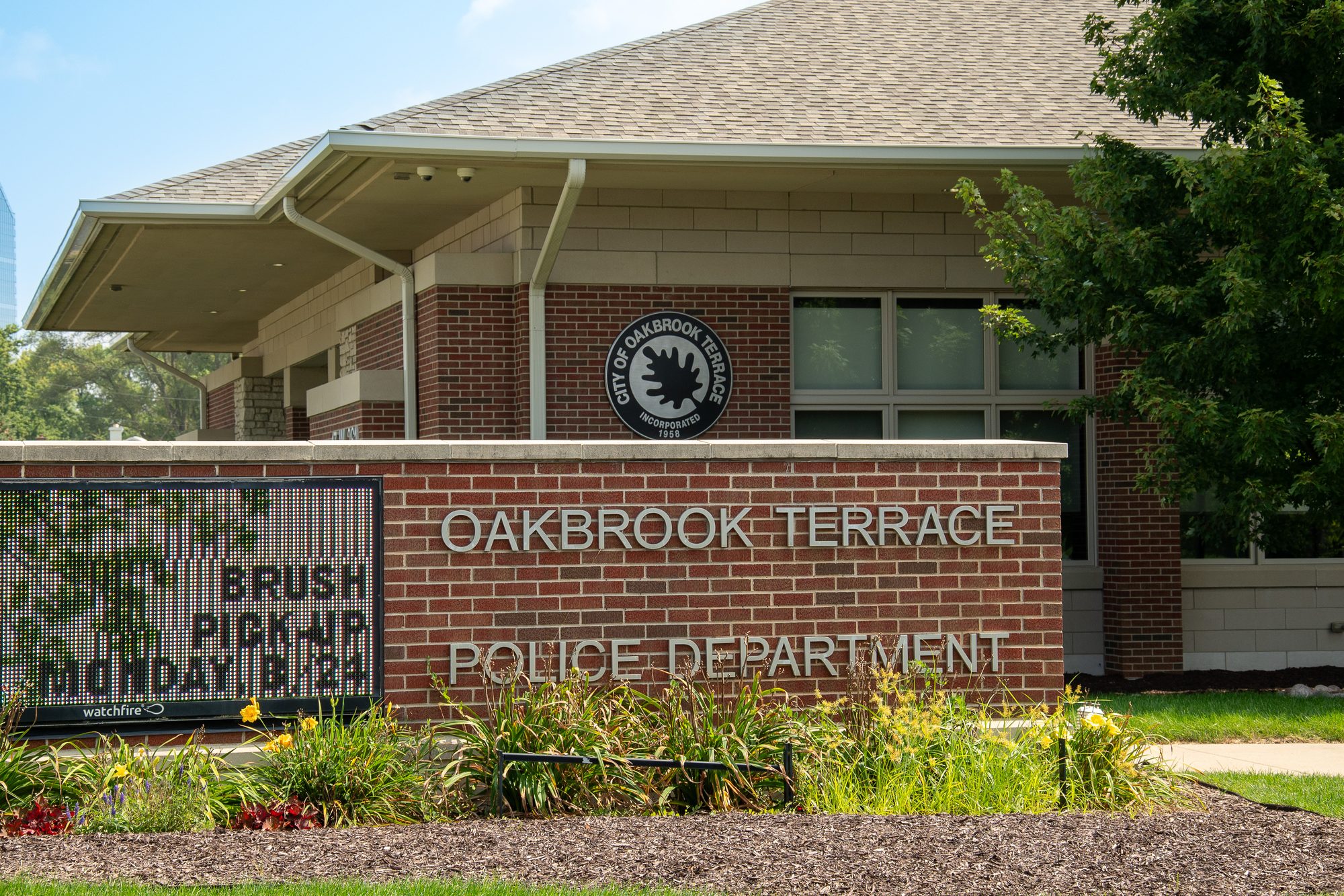 Brick police department building exterior with monument sign and city seal.