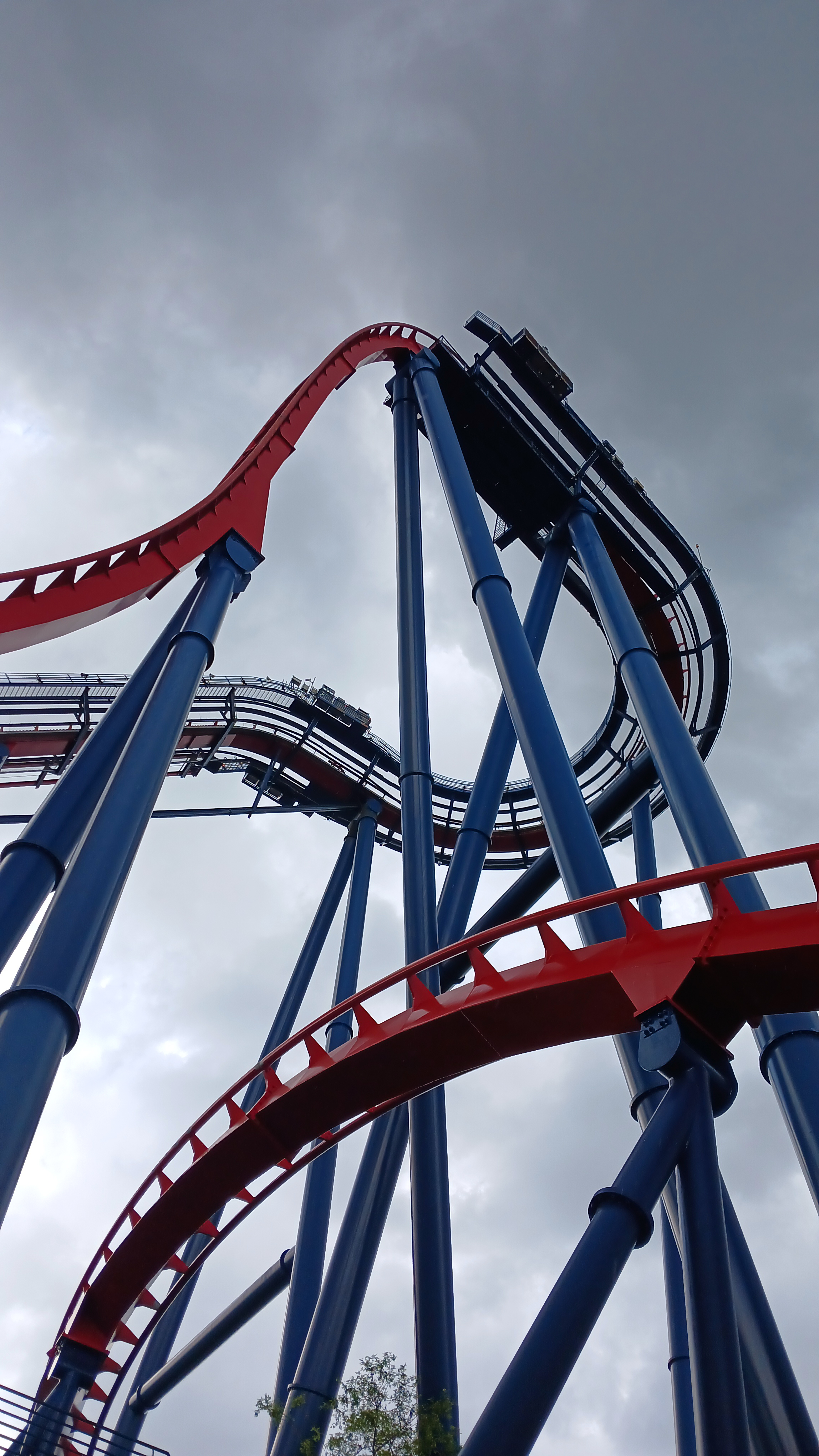 Roller coaster structure viewed from below against dark, heavy storm clouds.