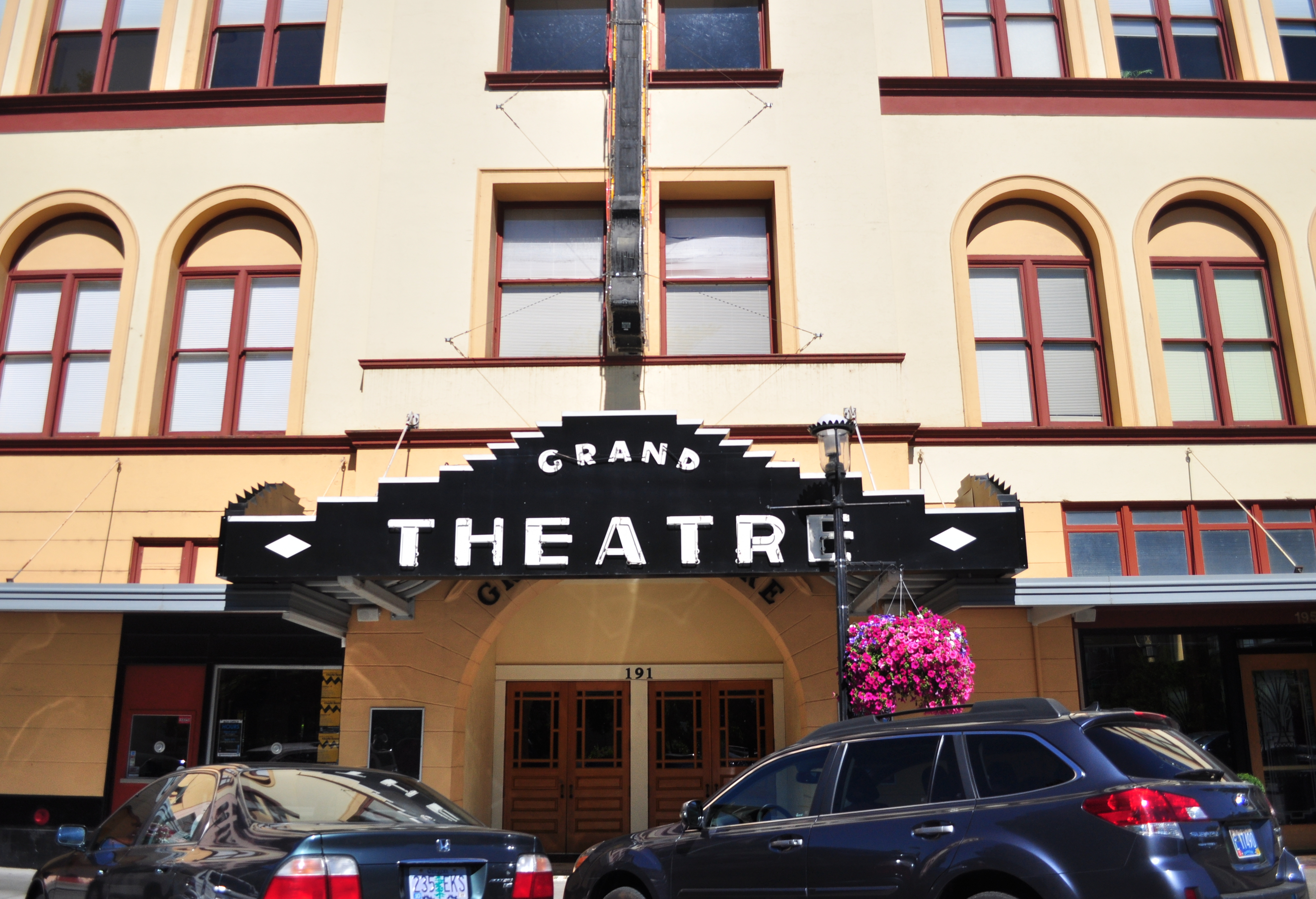 Historic theater building facade with a marquee sign reading Grand Theatre and arched windows.