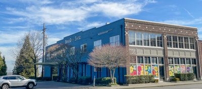 Two-story blue and brick commercial building with colorful murals on the lower exterior.